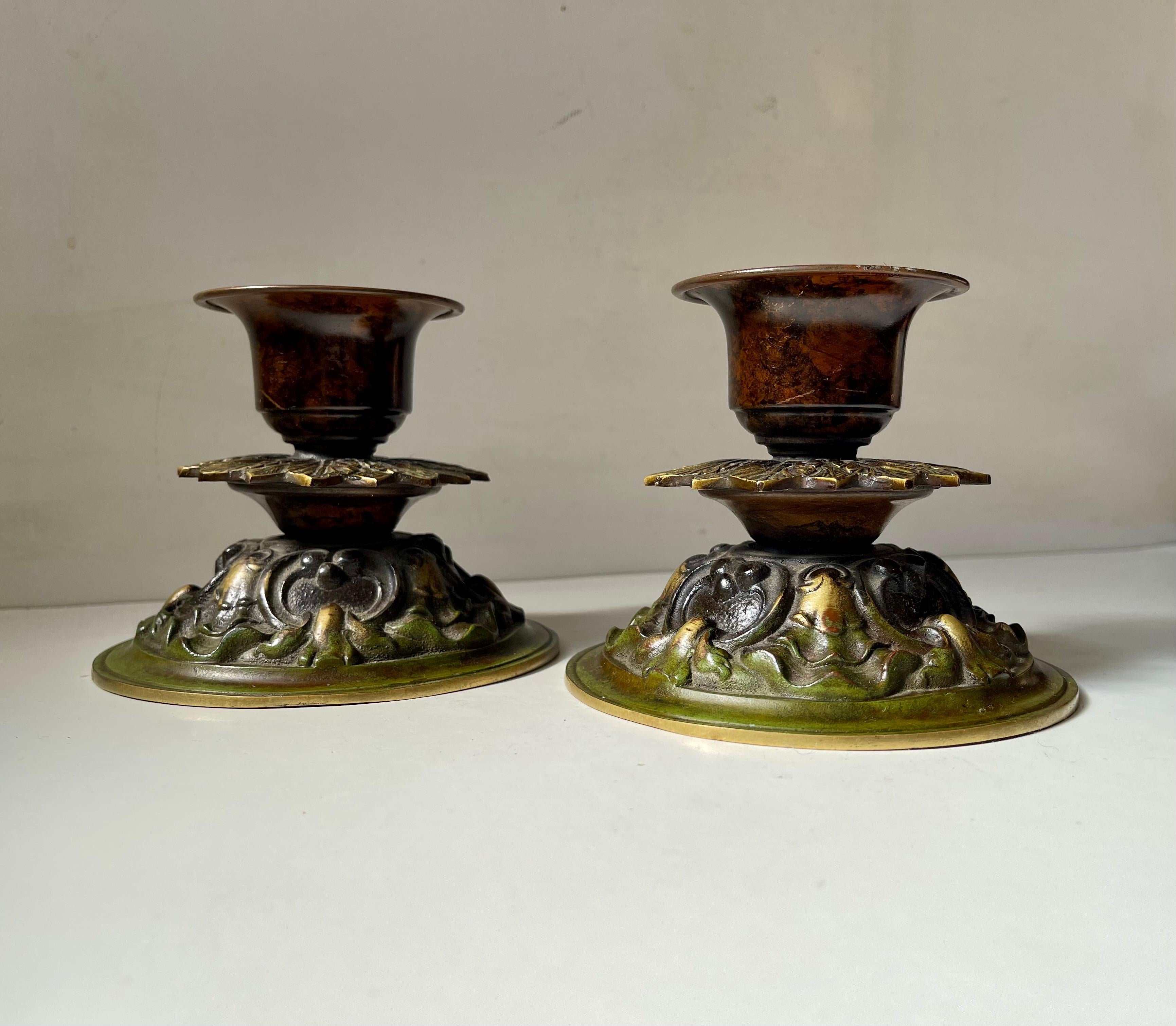 Coppia ornata di candelieri bassi in bronzo per candele da chiesa o da blocco. Dettagli floreali intricati e una vibrante patina verde. Realizzato in Danimarca negli anni '20 o '30 in uno stile che ricorda Just Andersen e Holger Fridericias.