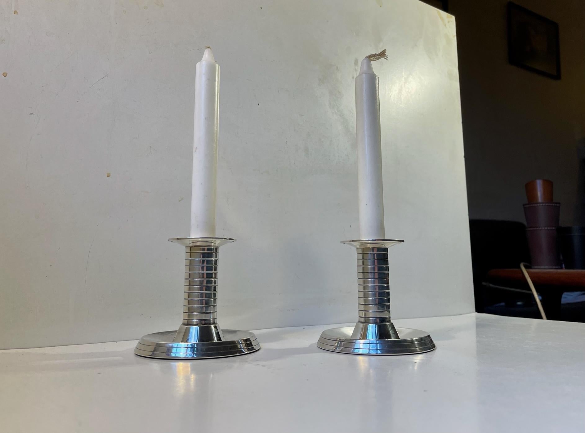A pair of silver plated candleholders for regular sized candles. Characteristic architectural Art Deco details with the 'stepped' bases and horizontal fluted stems. The silver plating is marked with danish hallmarks indicated by two towers. Designed