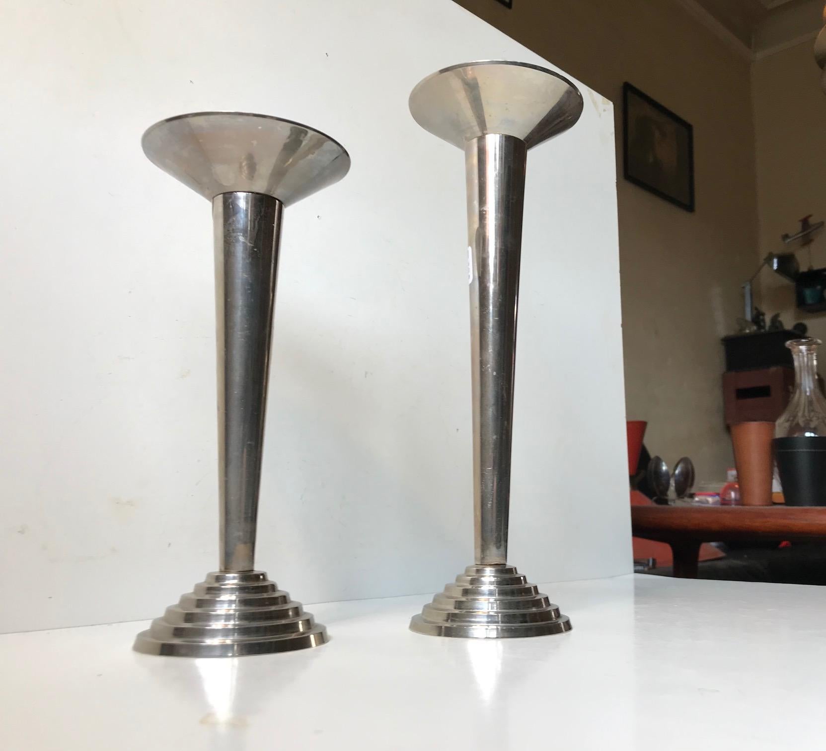 A set of Art Deco styled candlesticks. 'Staired' architecturally inspired base in engine turned aluminium. The tubes and candle holder are standard in size and made from stainless steel. Manufactured in Germany prior to WW II. Measures: Heights