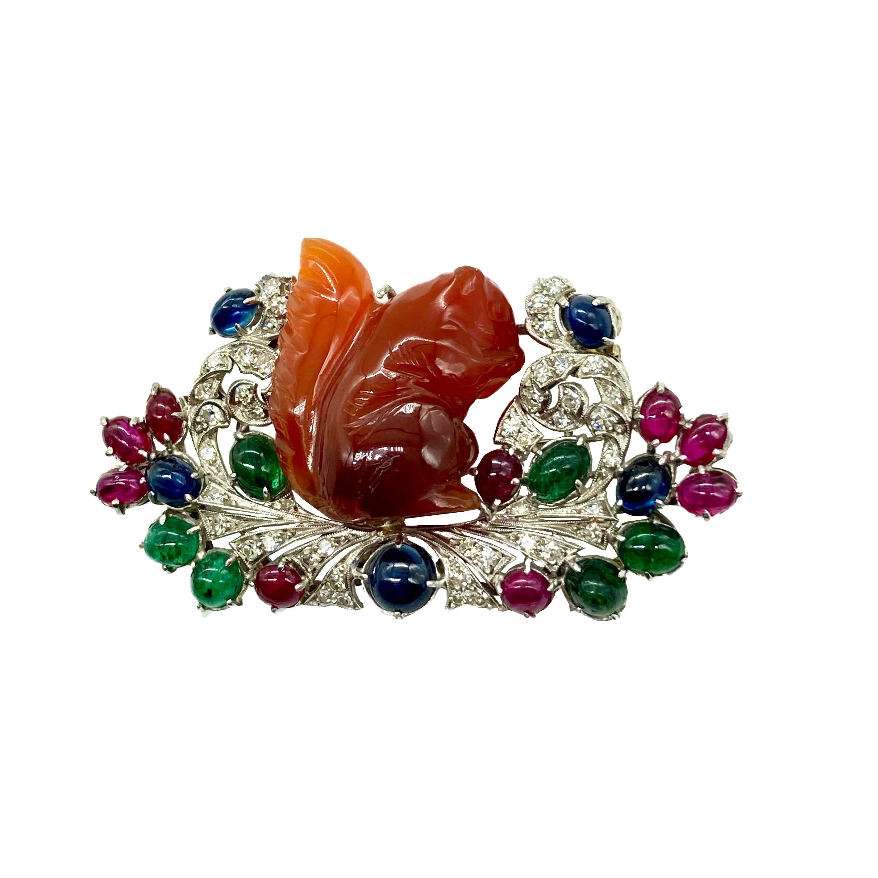A sophisticated Art Deco brooch centering a carved carnelian squirrel, embellished with diamonds, rubies, sapphires, and emeralds. Circa 1925.