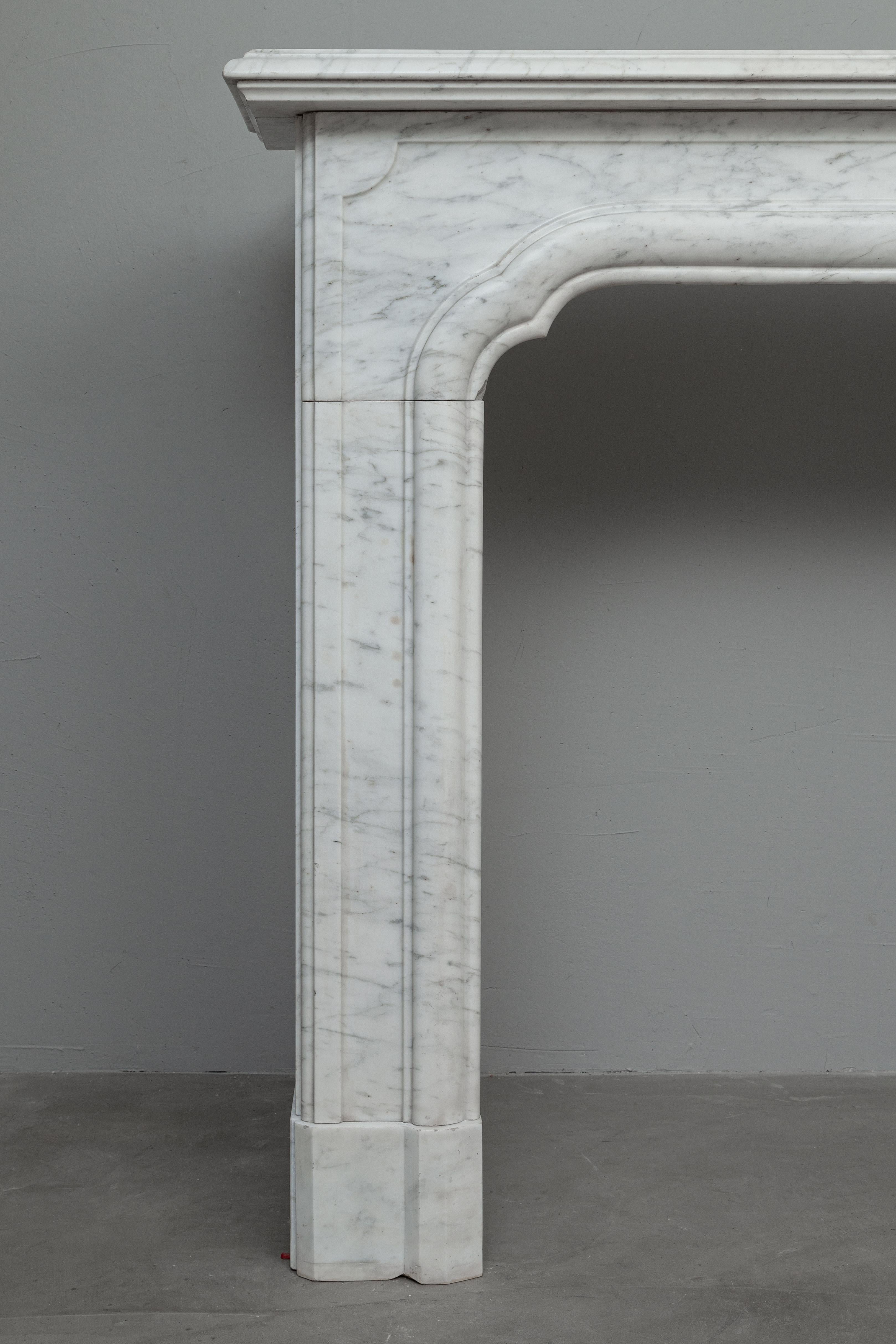 A beautiful sleek Art Deco fireplace made of Carrara marble. Simplicity and elegance meet in this antique Art Deco fireplace. The double profiled crook top and beautiful veining combined with the sleek design make this an asset for both a modern and