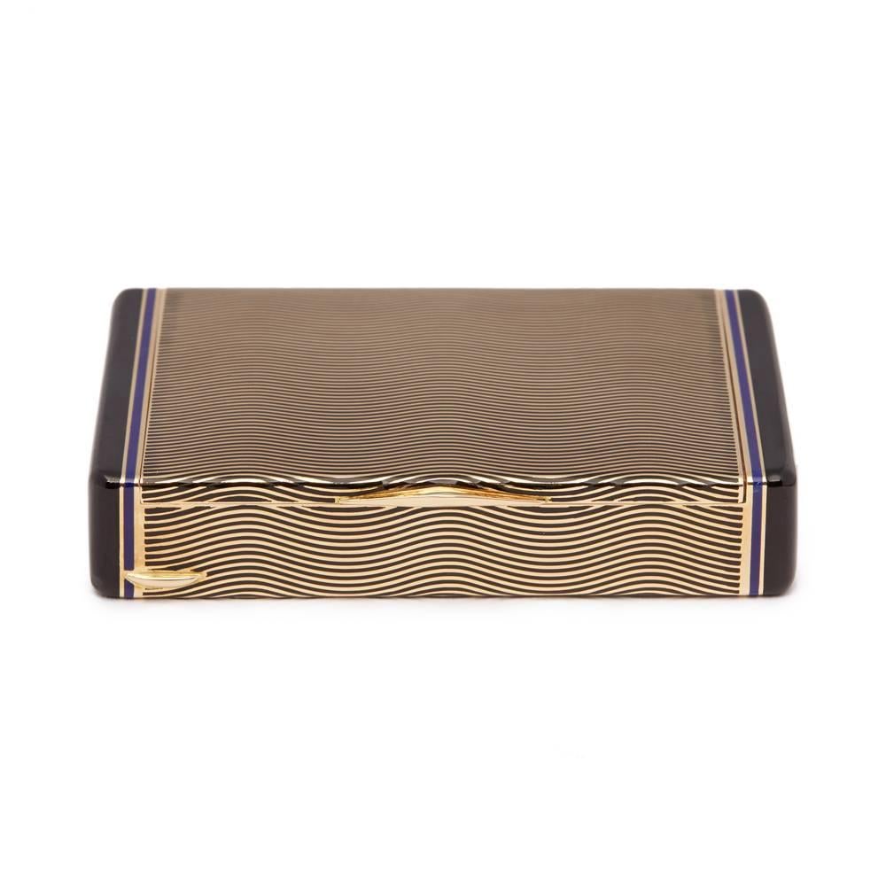 A Cartier Paris 18 karat yellow gold box of Art Deco design thought to date from either the late 1920s-early 1930s. The box is decorated with a black and deep blue champlevé enamel design formed from undulating lines running horizontally across all