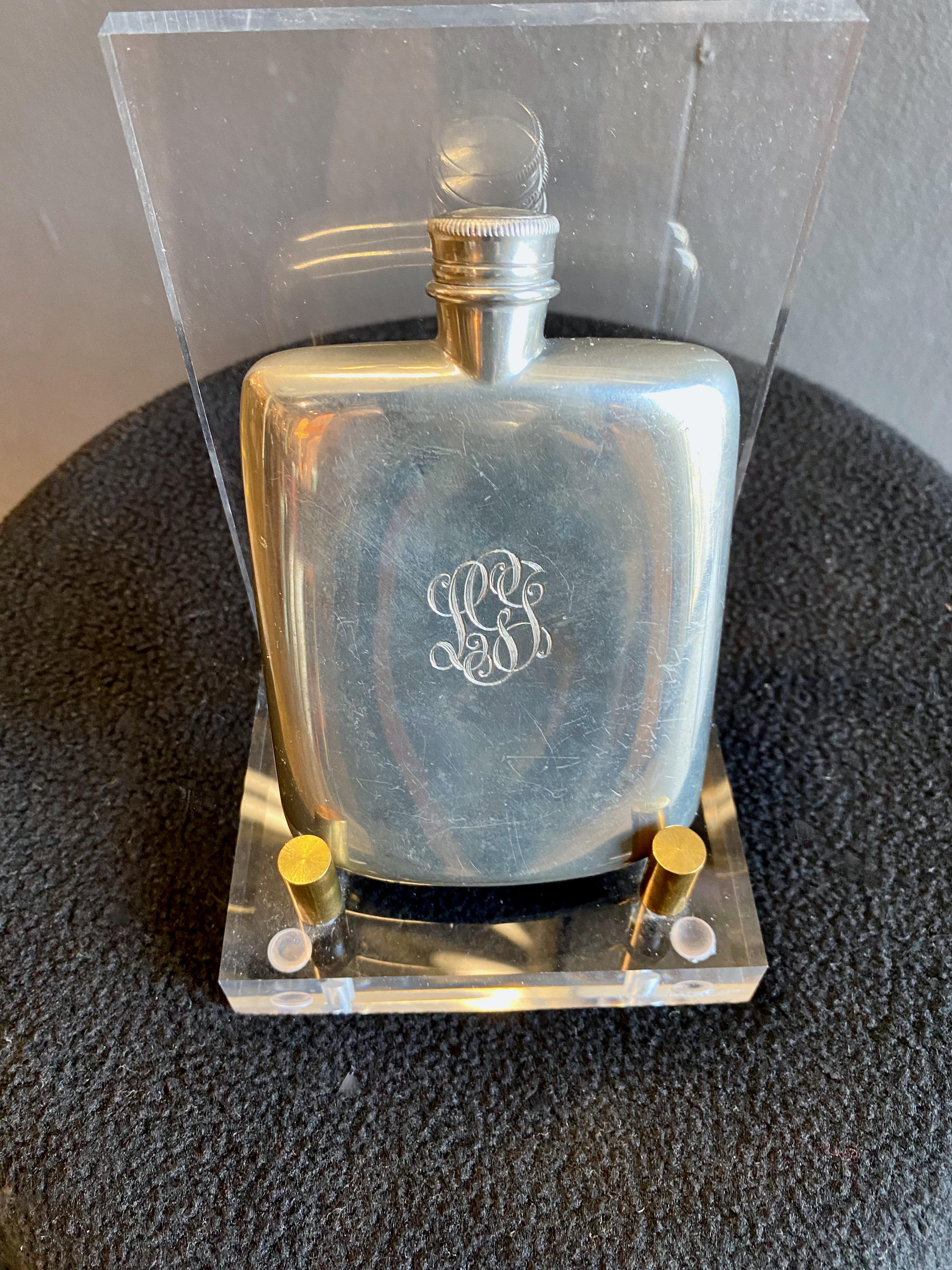 This is a classic Art Deco flask that has been designed by Cartier; however it was created in England--a hop, skip and a dunk from France. The flask carries a beautifully executed monogram to one side, leaving the 