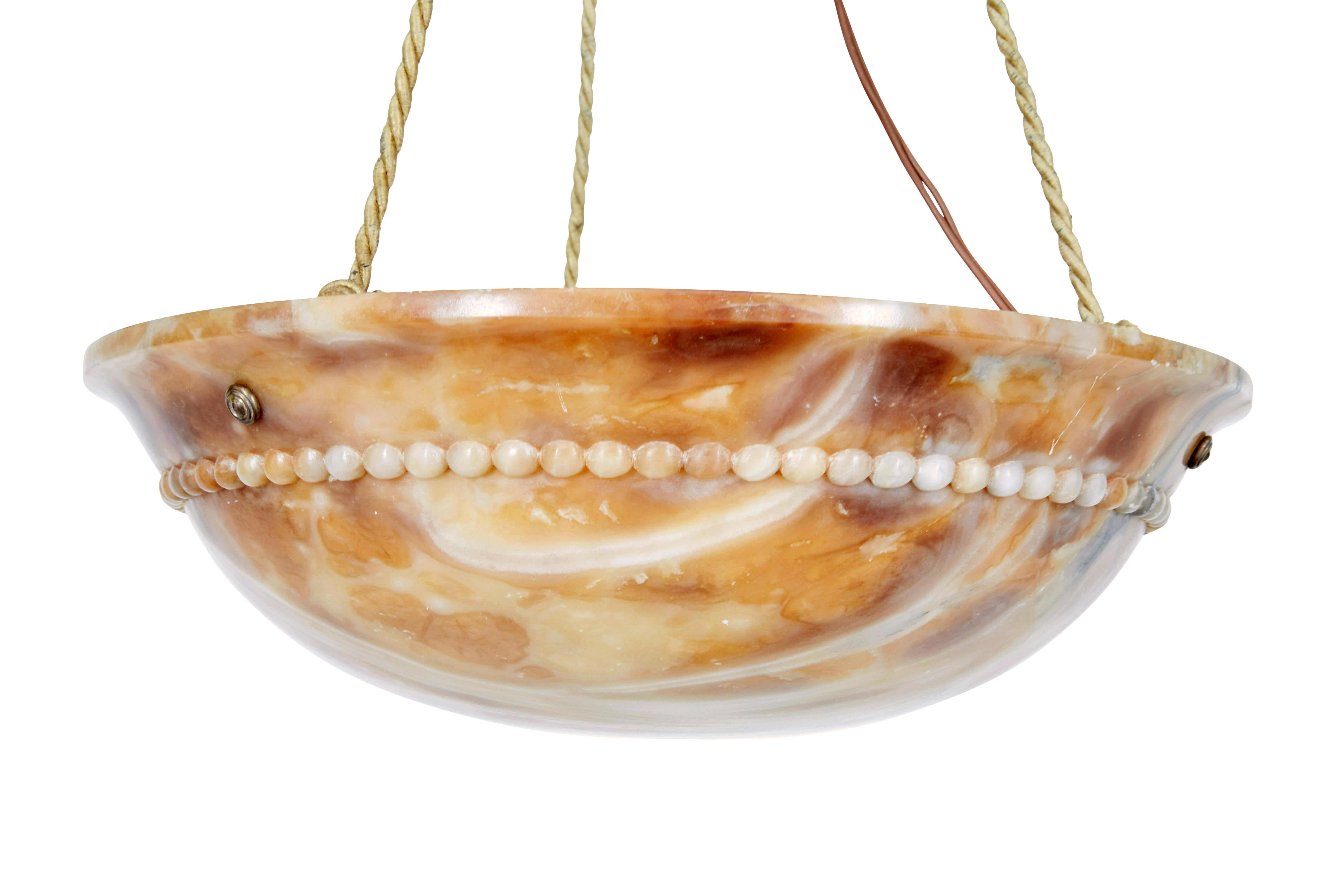 Art deco carved alabaster hanging pendant light circa 1930.

Beautifully naturally coloured hanging ceiling light made from solid alabaster. Carved to a dish form and with beaded detailing around the outside.  Suspended by 3 ropes which link to the
