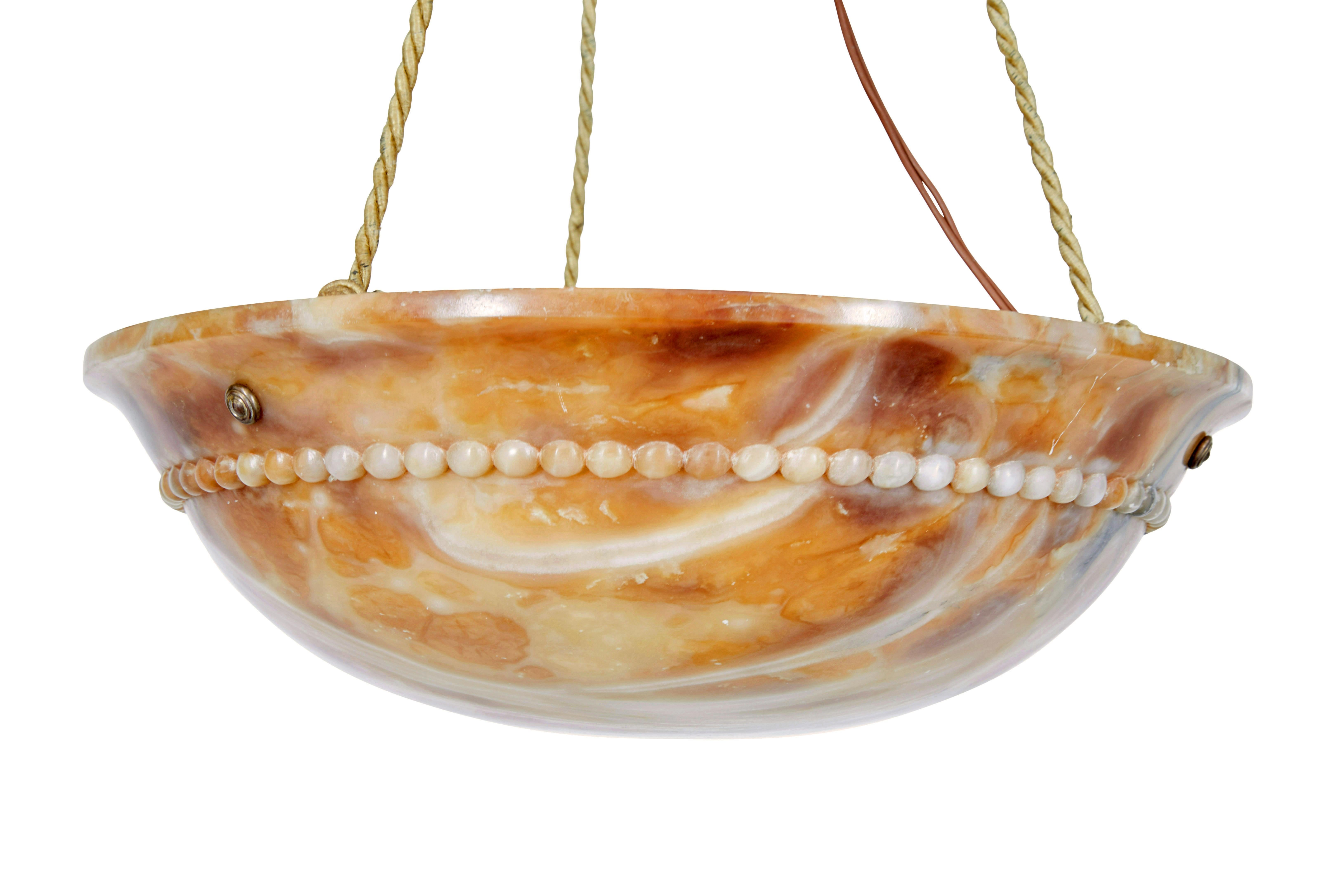 Art deco carved alabaster hanging pendant light circa 1930.

Beautifully naturally coloured hanging ceiling light made from solid alabaster. Carved to a dish form and with beaded detailing around the outside.  Suspended by 3 ropes which link to the