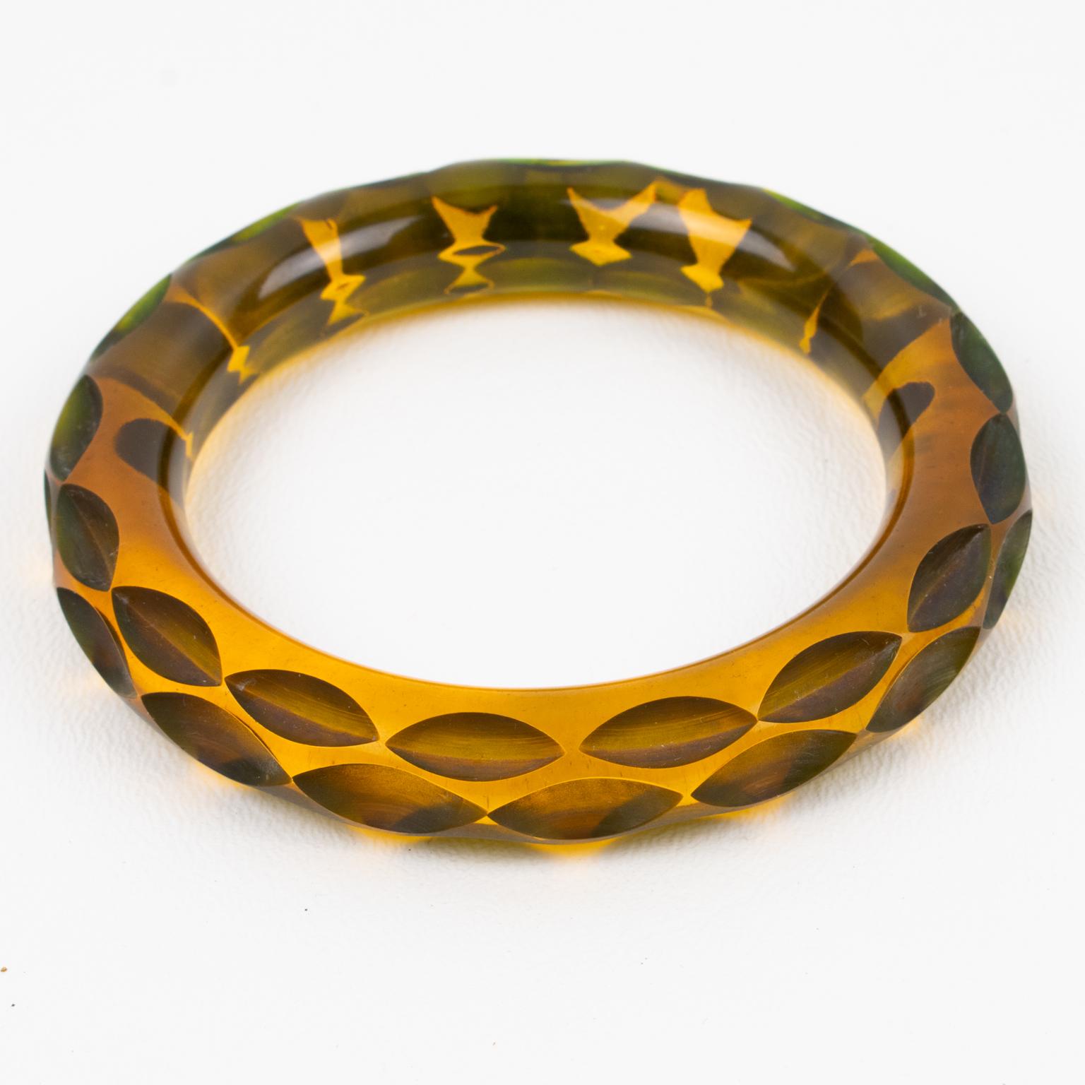This stunning transparent amber-color Bakelite bracelet bangle has a chunky domed shape with a deeply carved design. The piece boasts an intense orange-amber tone, all transparent with a green overtone on the edges. This Prystal quality piece has