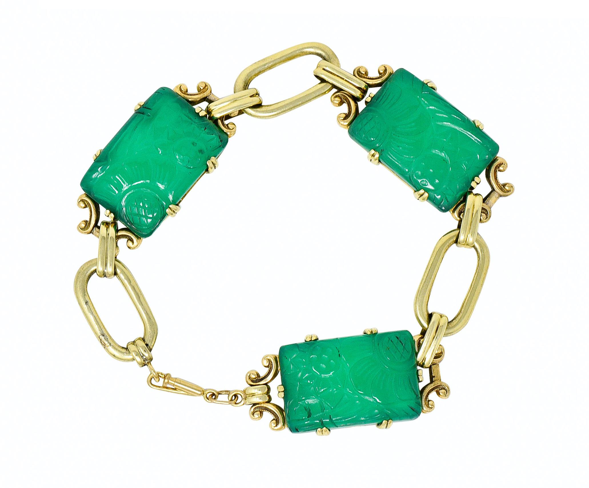Centering three rectangular tablets of chrysoprase, each measuring approximately 15.1 x 22.2 mm

A very well-matched translucent bluish-green color and deeply carved to depict a floral motif

Prong set in ornate whiplash frames, alternating with