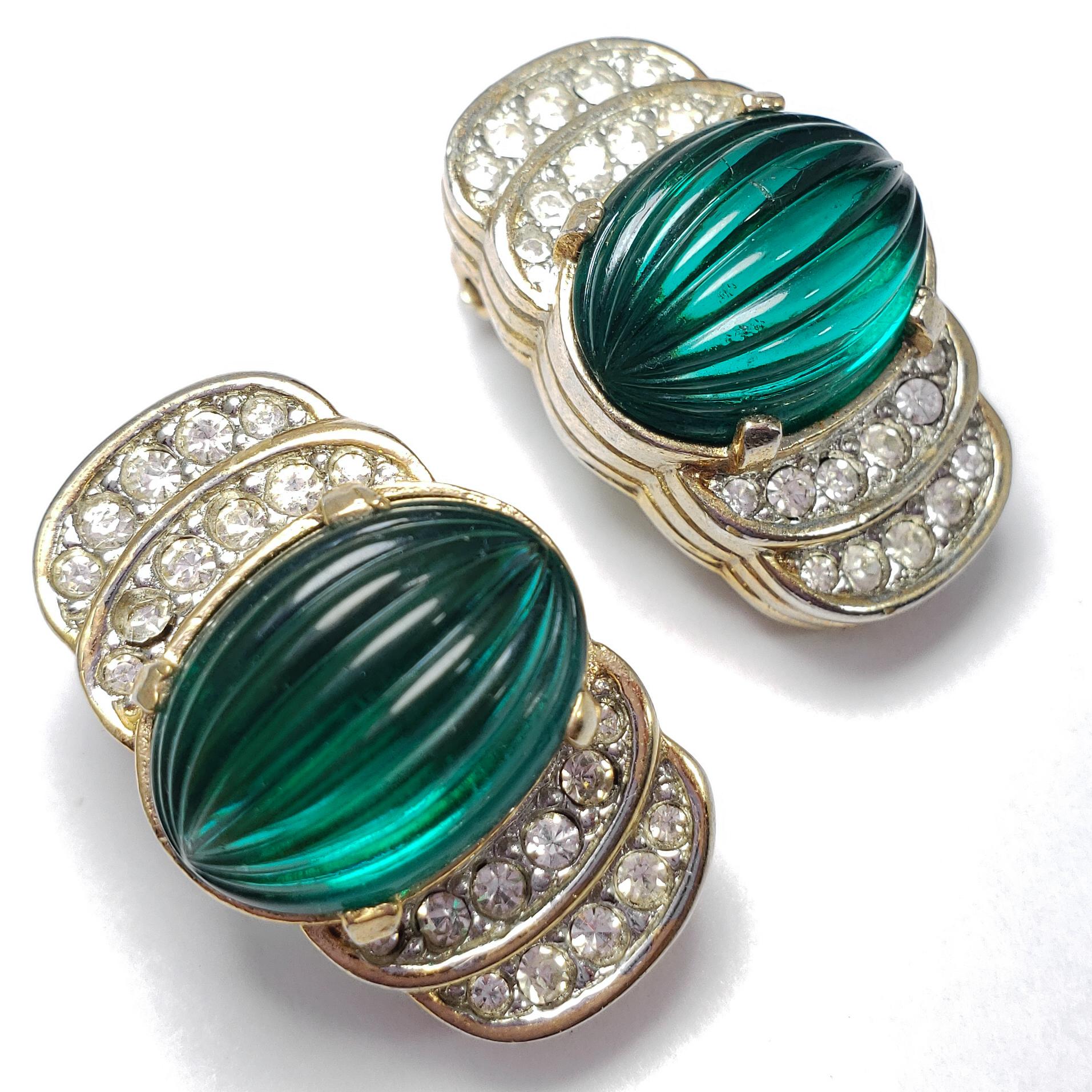 A luxurious pair of art-deco clip-on earring. Each features a single carved green crystal, accented with smaller clear stones. Set on gold-tone metal.

