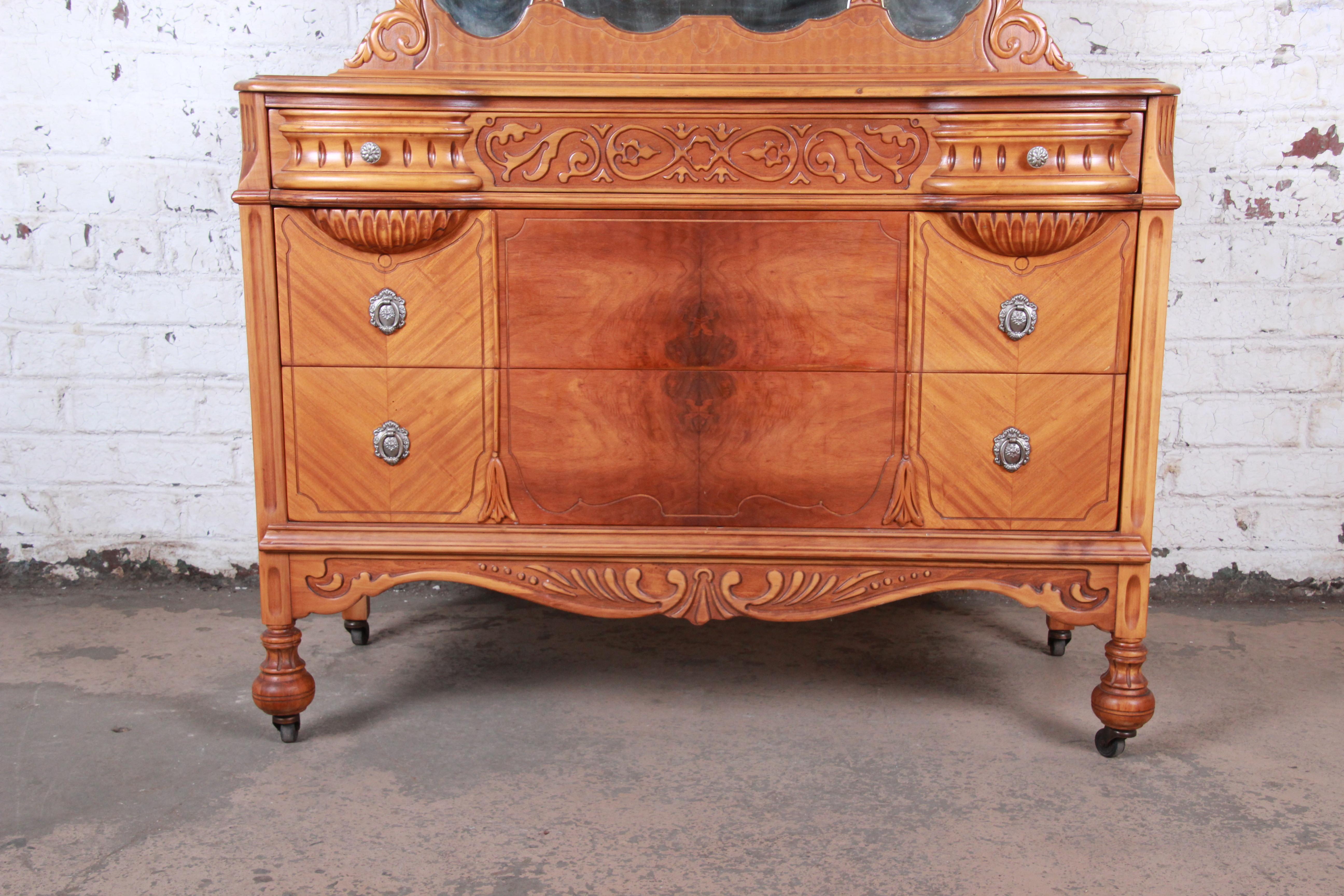 A gorgeous Art Deco ornate carved walnut dresser with mirror

USA, 1930s

Carved walnut + book-matched burled walnut drawer fronts + beveled mirror

Measures: 49