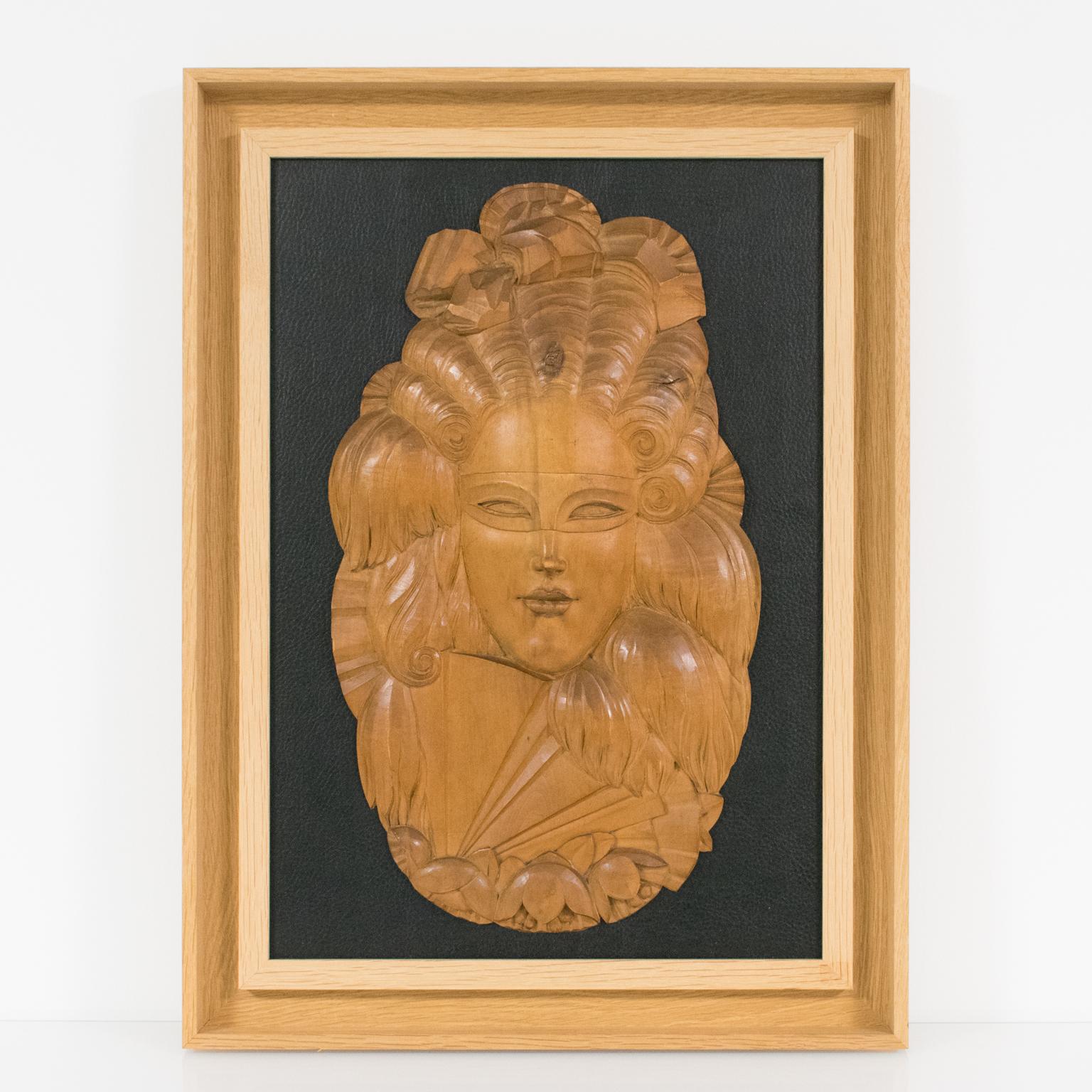 This extraordinary Art Deco wood panel or wall-mounted sculpture features a spectacular Venetian mask. The rare piece was crafted in France circa 1930. The sculpted panel boasts finely detailed carving on a light-colored natural wood. The decorative