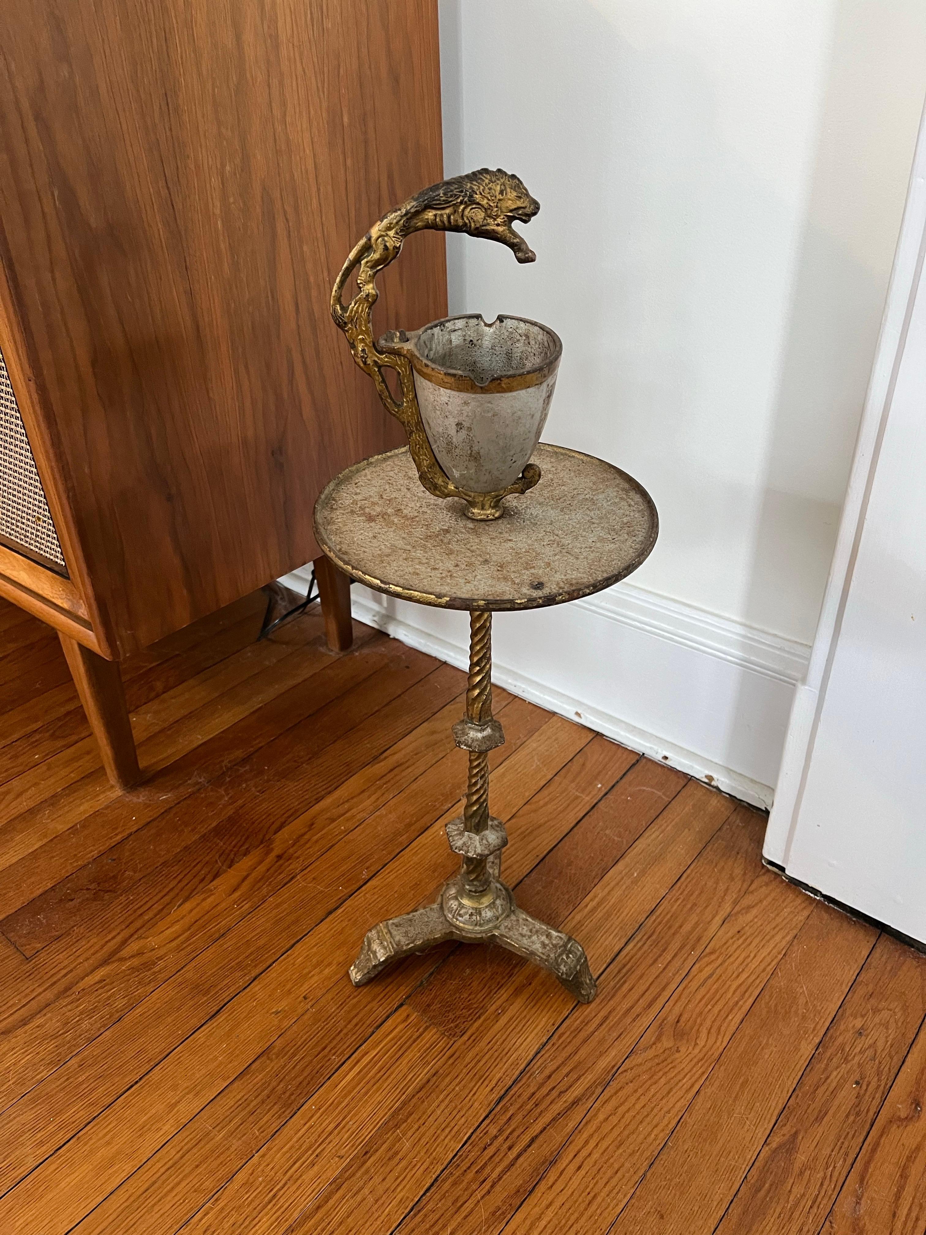 Gran pieza de época. Soporte o cenicero para fumar de hierro Art Decó con cenicero extraíble. Base y tablero de hierro dorado. Empuñadura con decoración de león. Patente marcada App. Para el nº 5.