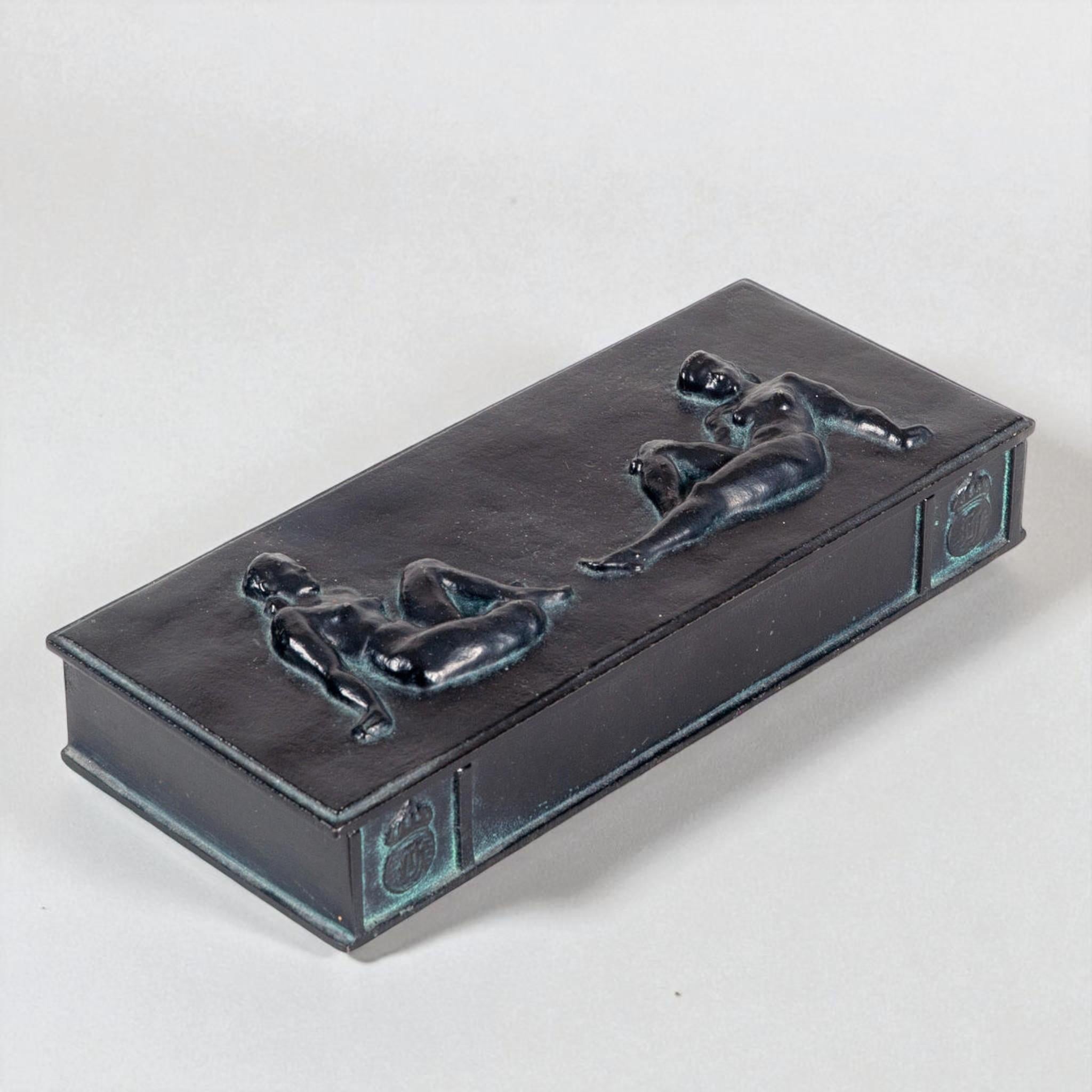 Elegant cast iron box manufactured by Husqvarna, Sweden, during the 1930s. The lid is decorated with finely sculpted reclining nude figures in relief, displaying exceptional craftsmanship and a refined Art Deco aesthetic. The surface features a deep