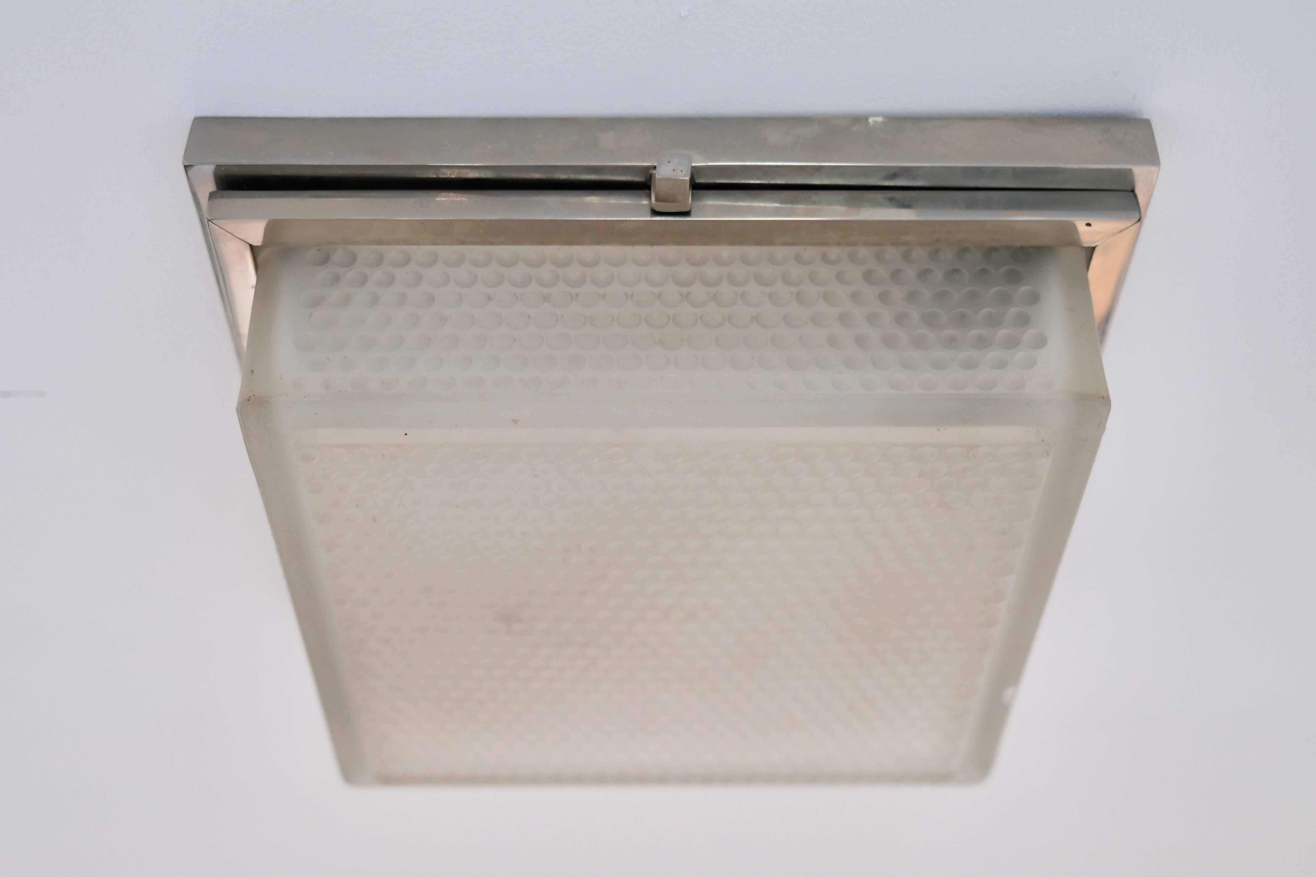 Un pezzo intramontabile del design Art Déco francese, questa lampada da soffitto quadrata degli anni '30 offre semplicità ed eleganza. Il suo paralume in vetro smerigliato e testurizzato è perfettamente incorniciato da una montatura in ottone con