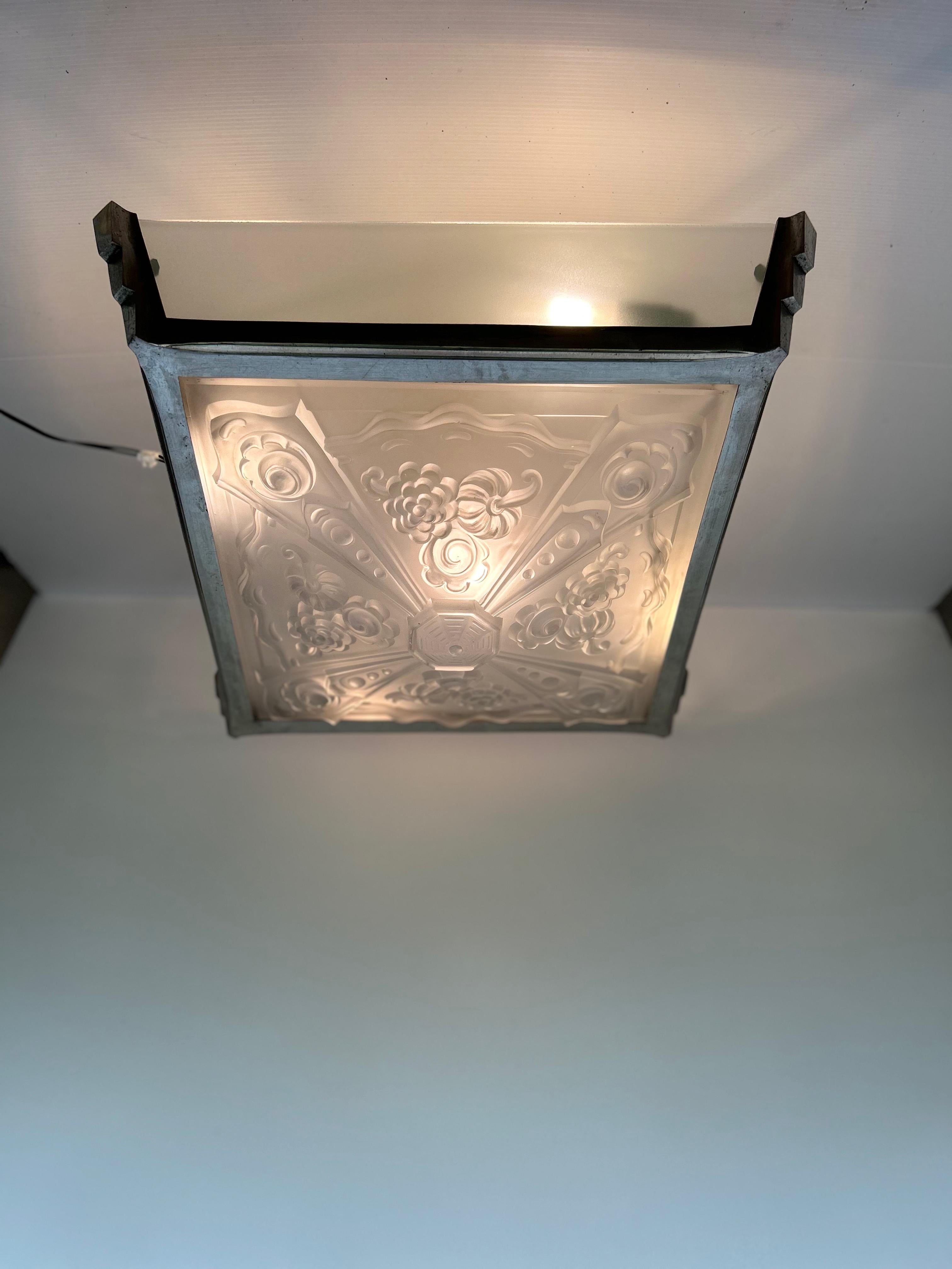 Large Art Deco ceiling light, circa 1930.
Nickel-plated bronze frame. Central molded glass pane attributed to Vals Saint Lambert.
4 sandblasted glass side panels.
In perfect condition.
Electric, 5 lights, E14 sockets.

Total height: 19 cm
Width: 50