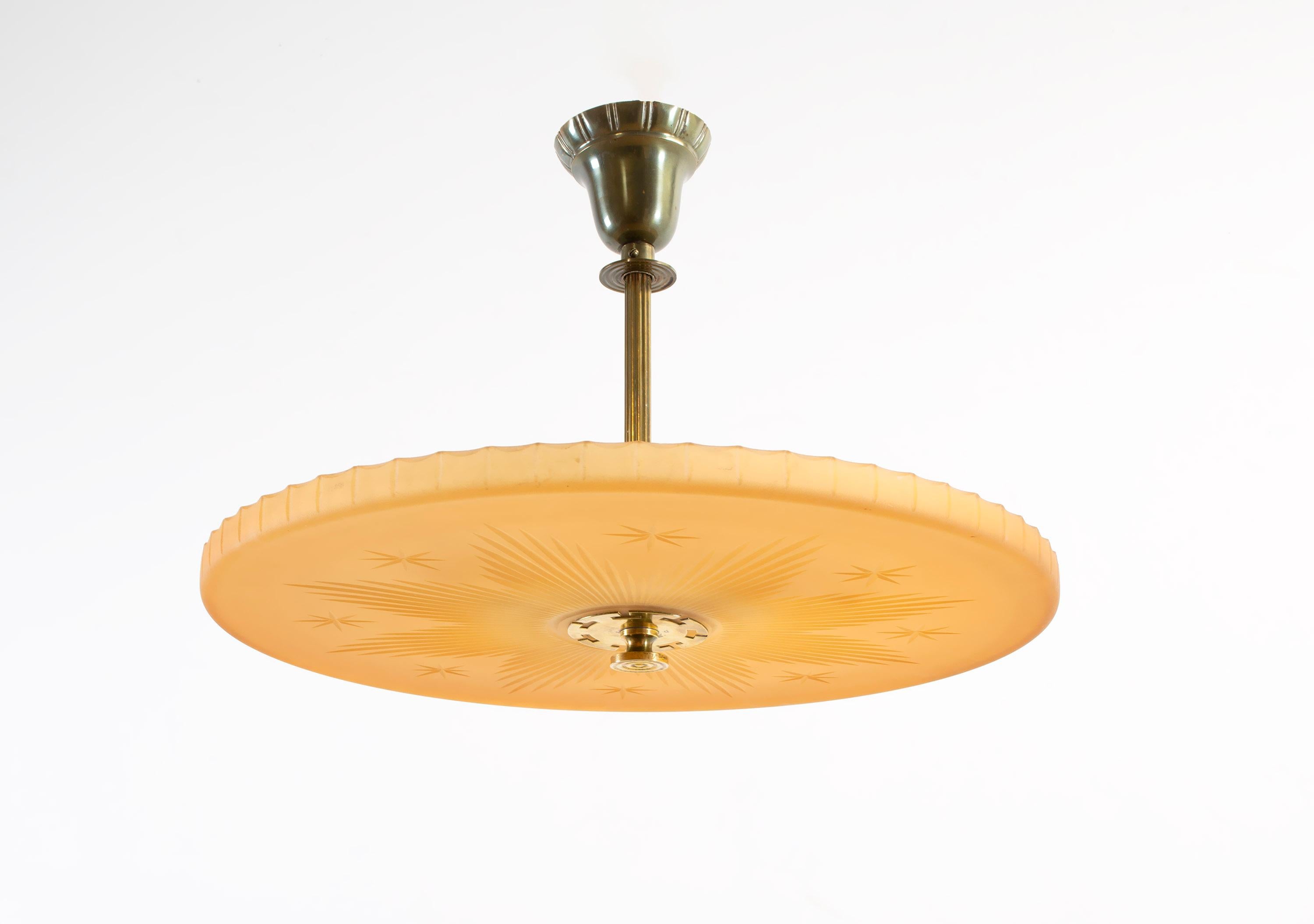 Wonderful and decorative ceiling lamp in Havana glass and brass stem. Designed and made in Sweden by Orrefors from circa 1930s second half. The lamp is fully working and in very vintage condition. The lamp is fitted with three E27 bulb holders