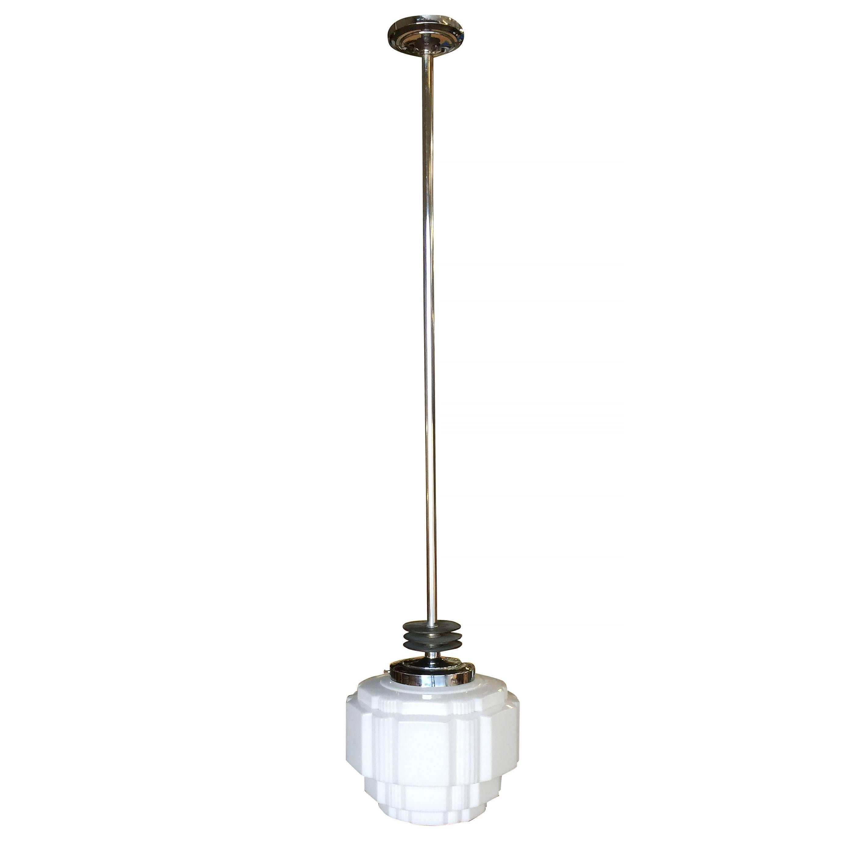 Rare Art Deco chrome ceiling pendant with enameled black streamline accents and stepped milk glass geometric school house style glass globe with hand-painted Art Deco design.

Dimensions of light are 16” high.

Drop can be 16