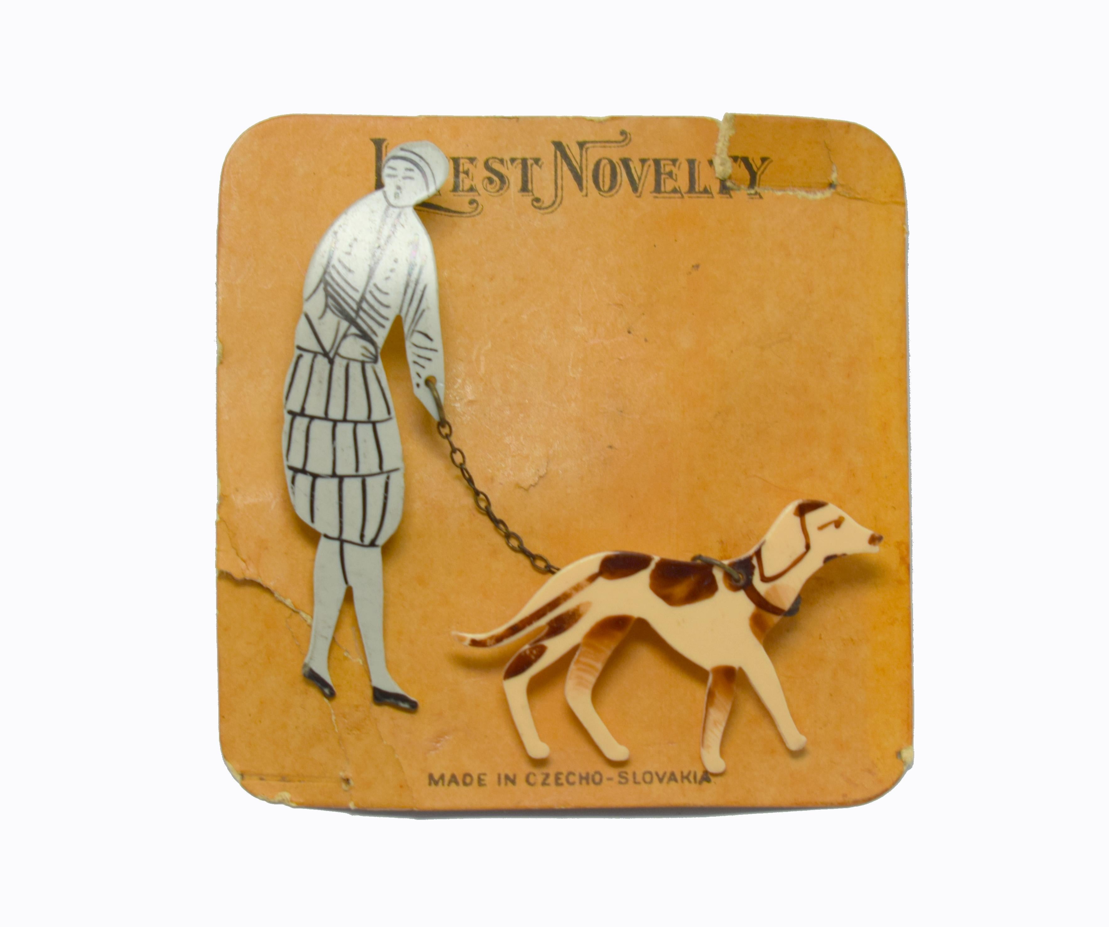 Beautiful piece of jewellery dating to the 1930's is this novelty brooch depicting a 1920's/30's lady walking her dog, possibly an Airedale. The lady is in the fashion of the day including a cloche hat and court shoes. Still on it's original card