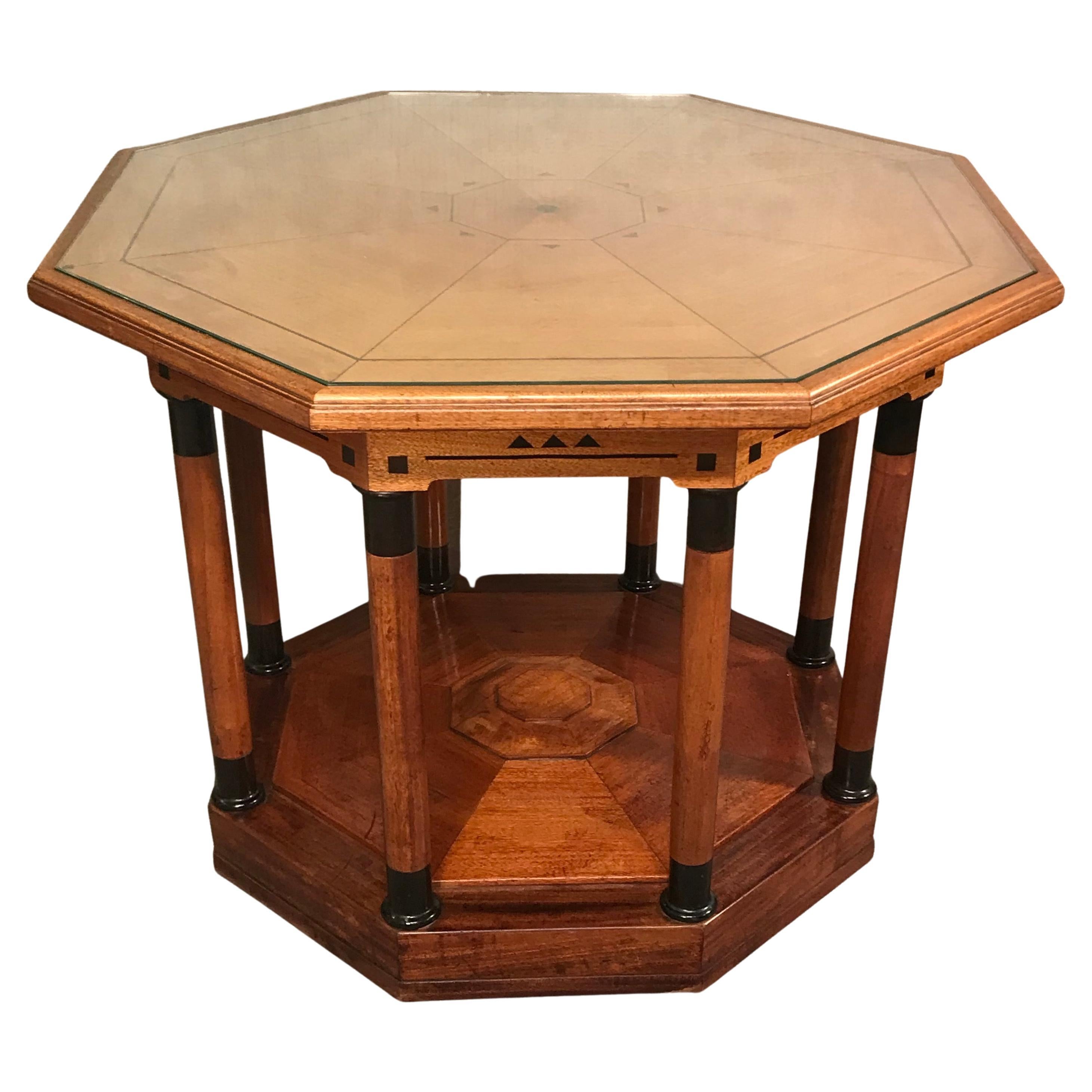 This unique Art Deco table dates back to around 1910-20. It comes from Germany. The table has a walnut veneer and is decorated with geometric ebonized inlays of different types of wood. It has an octagonal top with a protecting glass on top. The