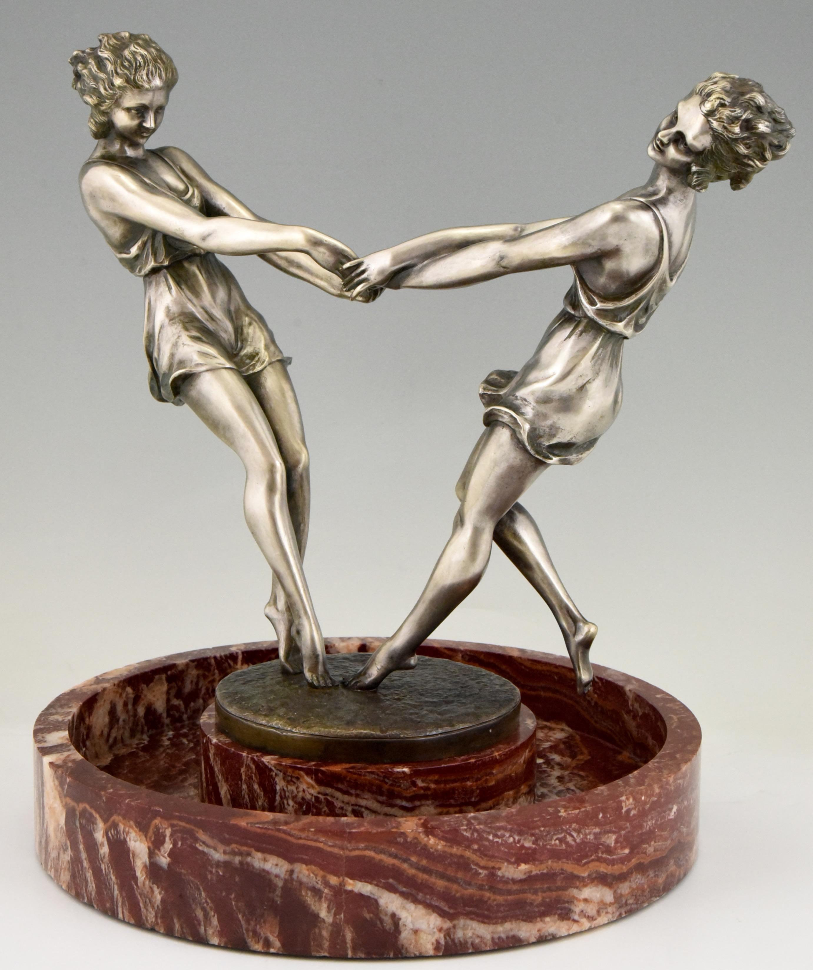 Centre de table circulaire en marbre, tourbillonnant et spectaculaire, avec une sculpture en bronze de deux danseuses se tenant par la main, réalisée par l'artiste français Andre Gilbert, vers 1925.
Le bronze a une patine argentée.

Ce modèle est