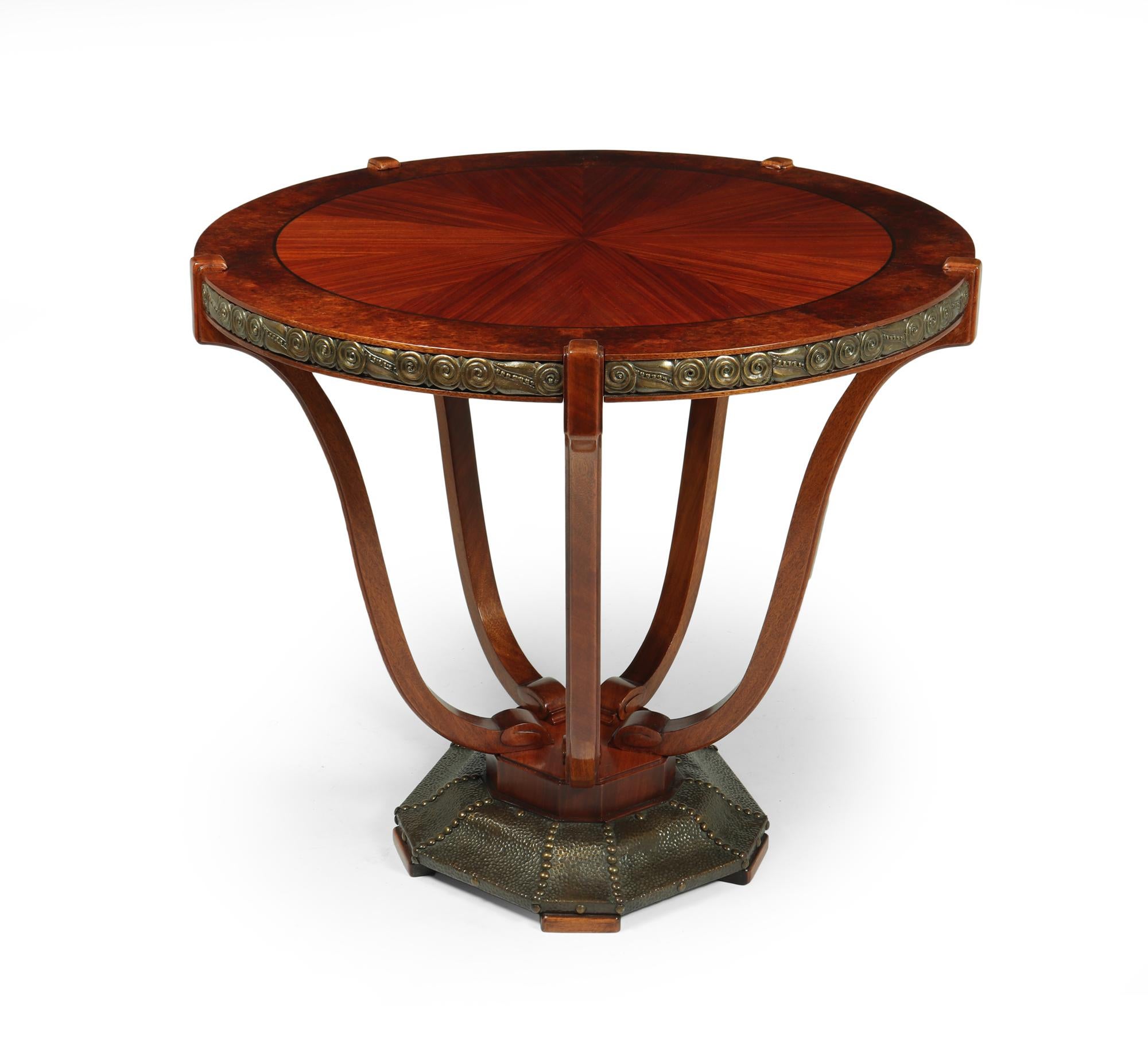 An exceptional quality and style centre table by Maurice Dufrene produced in Paris France 1920-1925 this table has a segmented santos rosewood top cross-banded in amboyna with ebony string lining it has cast bronze mounts five solid mahogany shaped