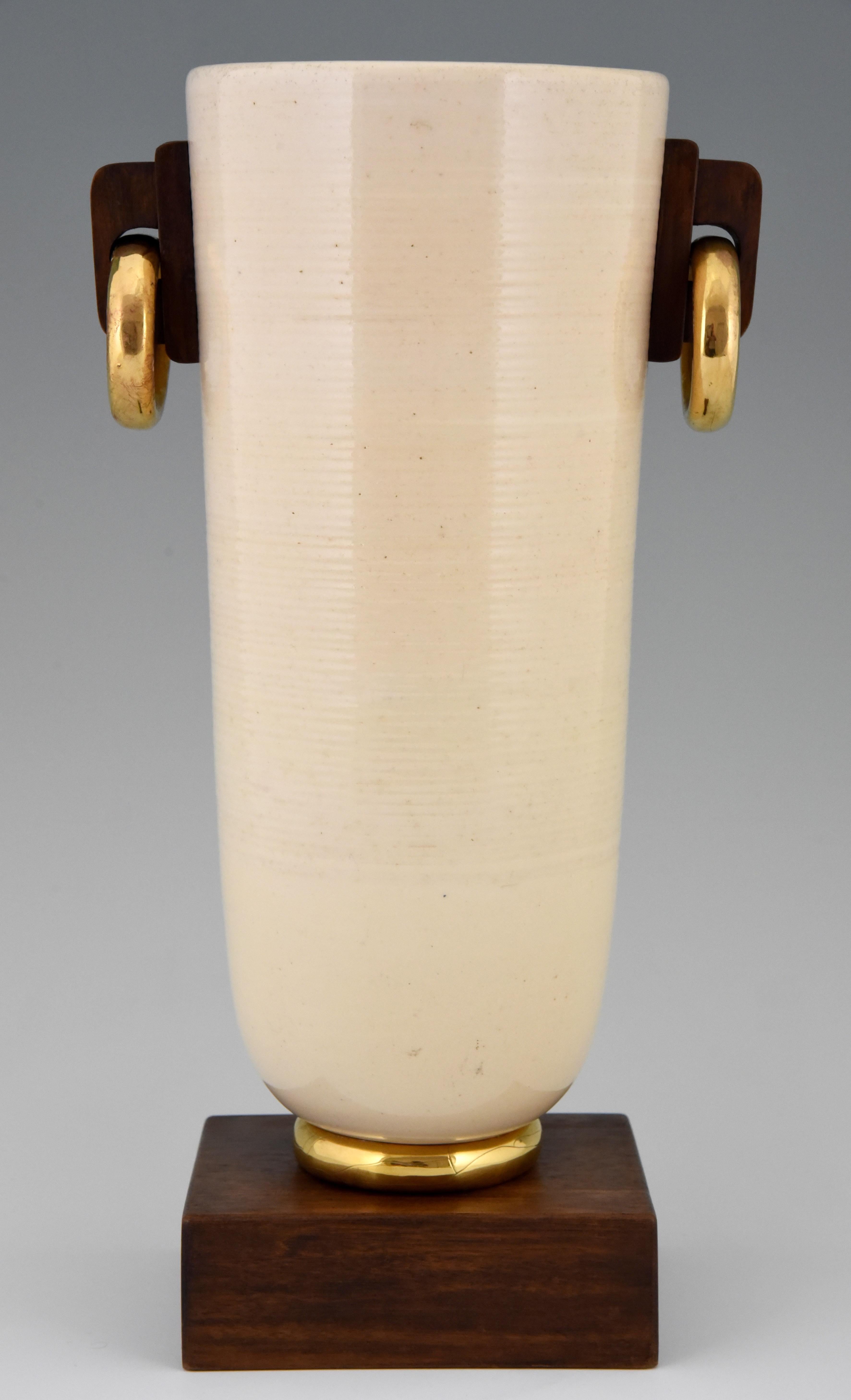Tall Art Deco vase in cream and gold ceramic with wooden handles and base. In the style of Luc Lanel. 
The same vase has been auctioned at Millon Auctioneers. 

Similar vases are illustrated in:
Lanel, Luc & Marjolaine. ?Dominique Forrest.