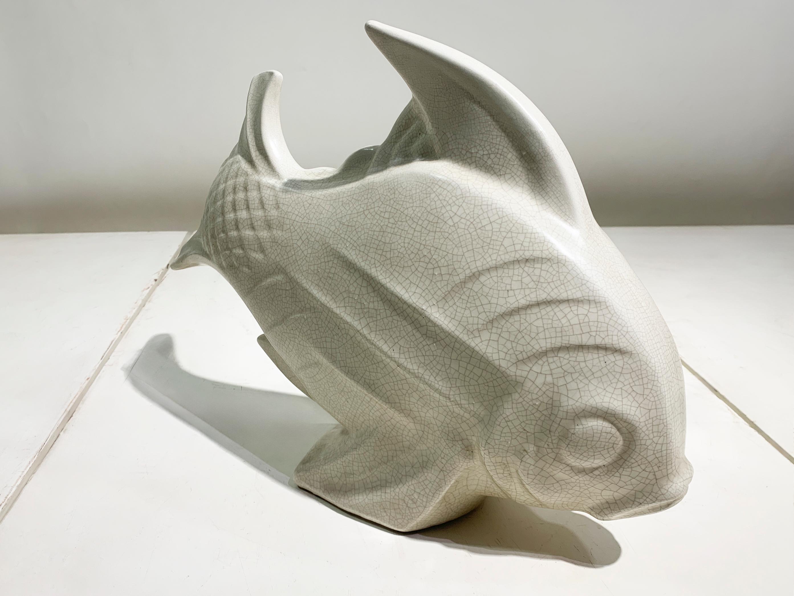Évoquez le charme serein de la mer avec cette exquise sculpture de poisson en céramique Art déco, délicieux témoignage de la tradition du milieu du 20e siècle.  design. Réalisée avec un souci de formes organiques et de textures subtiles, cette pièce
