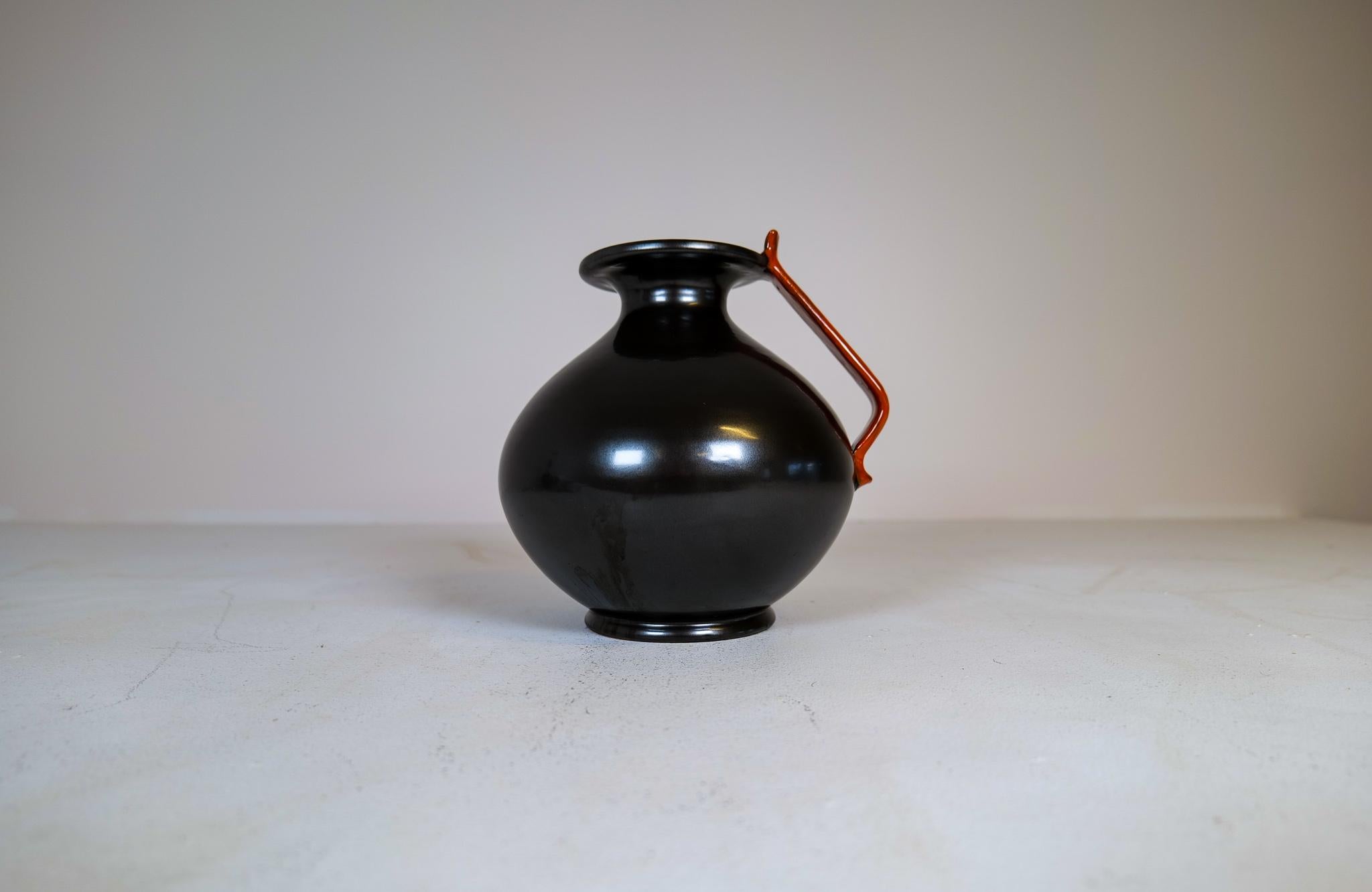 This globe vase was manufactured at Ekeby in Sweden 1930s.
With its typical of its time globe shape and with a black glaze orange top this vase stands out. 

Nice vintage condition.

Dimensions: H 25 cm D 25 cm.

  
