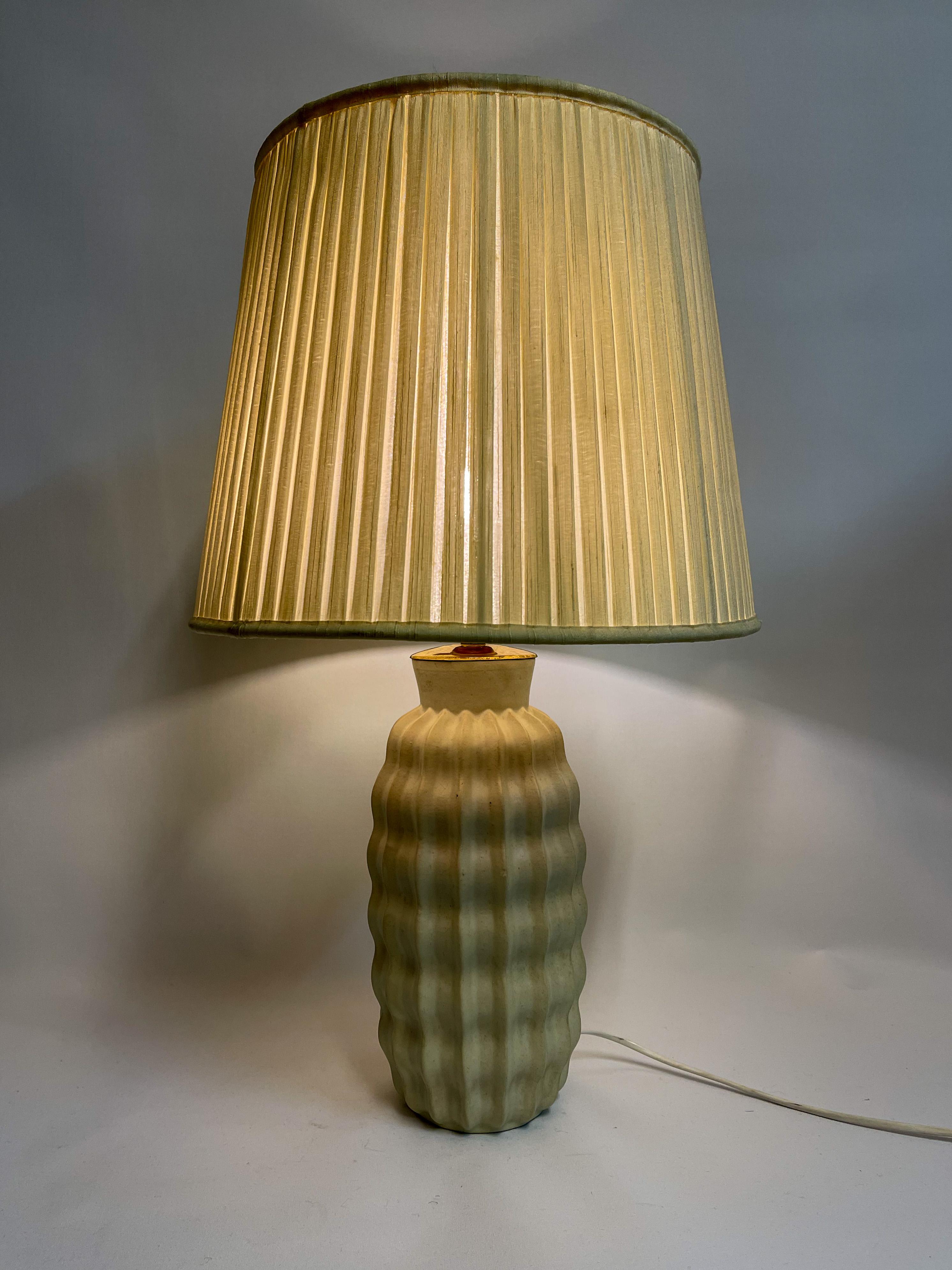Cette magnifique lampe de table Art Déco en céramique a été fabriquée par Upsala Ekeby en Suède, dans les années 1930-1940.
Il a une forme et une figure incroyables et une belle glaçure. Son aspect organique en fait une belle édition pour toute