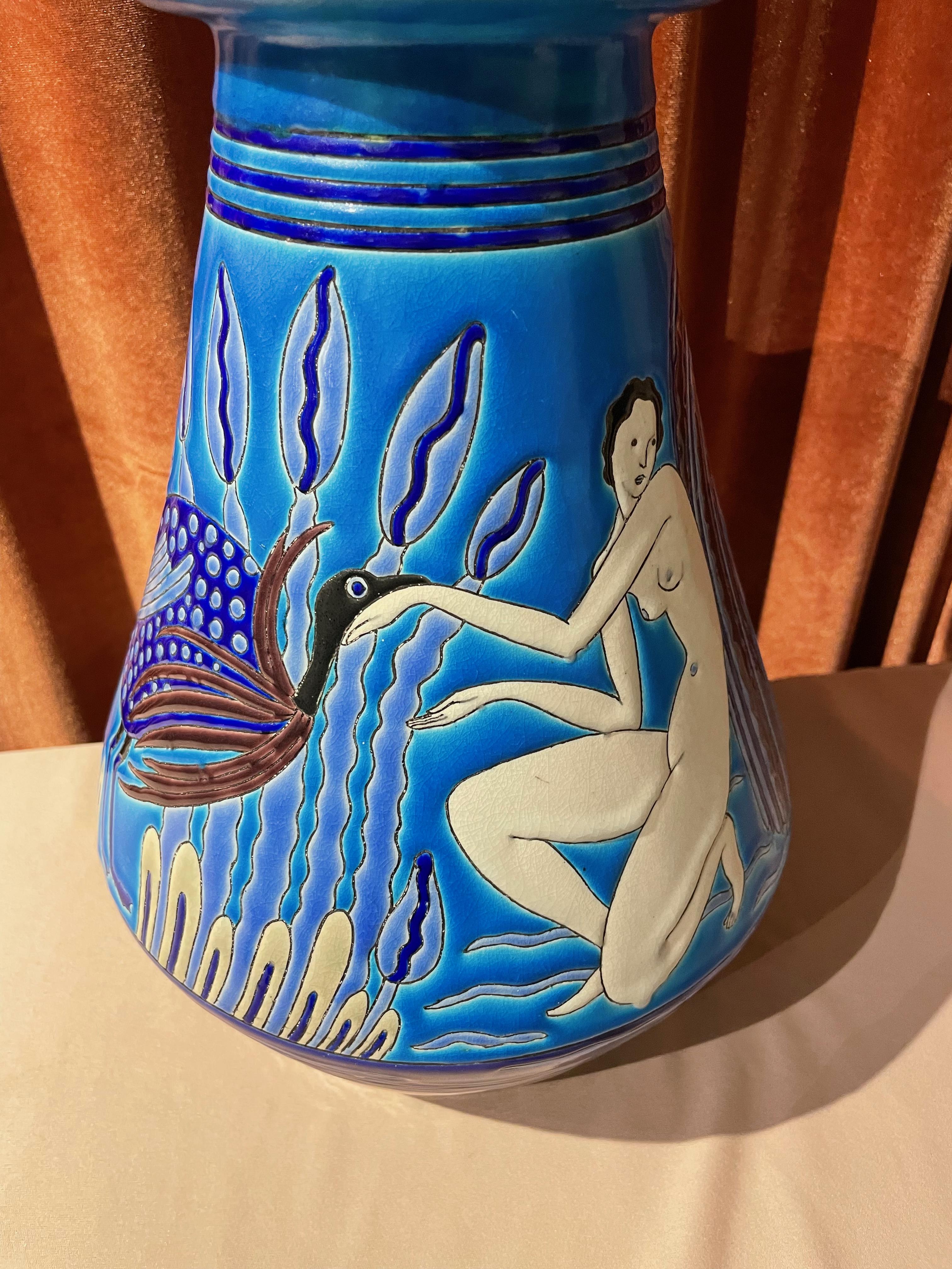 “Aux Baigneuses” is a fine Longwy Primavera Art Deco ceramic vase with 2 bathing nudes, a peacock, and ibex in blue, purple, black, and white shades. Longwy made this French Art Deco vase for Atelier Primavera, the design studio of the Paris