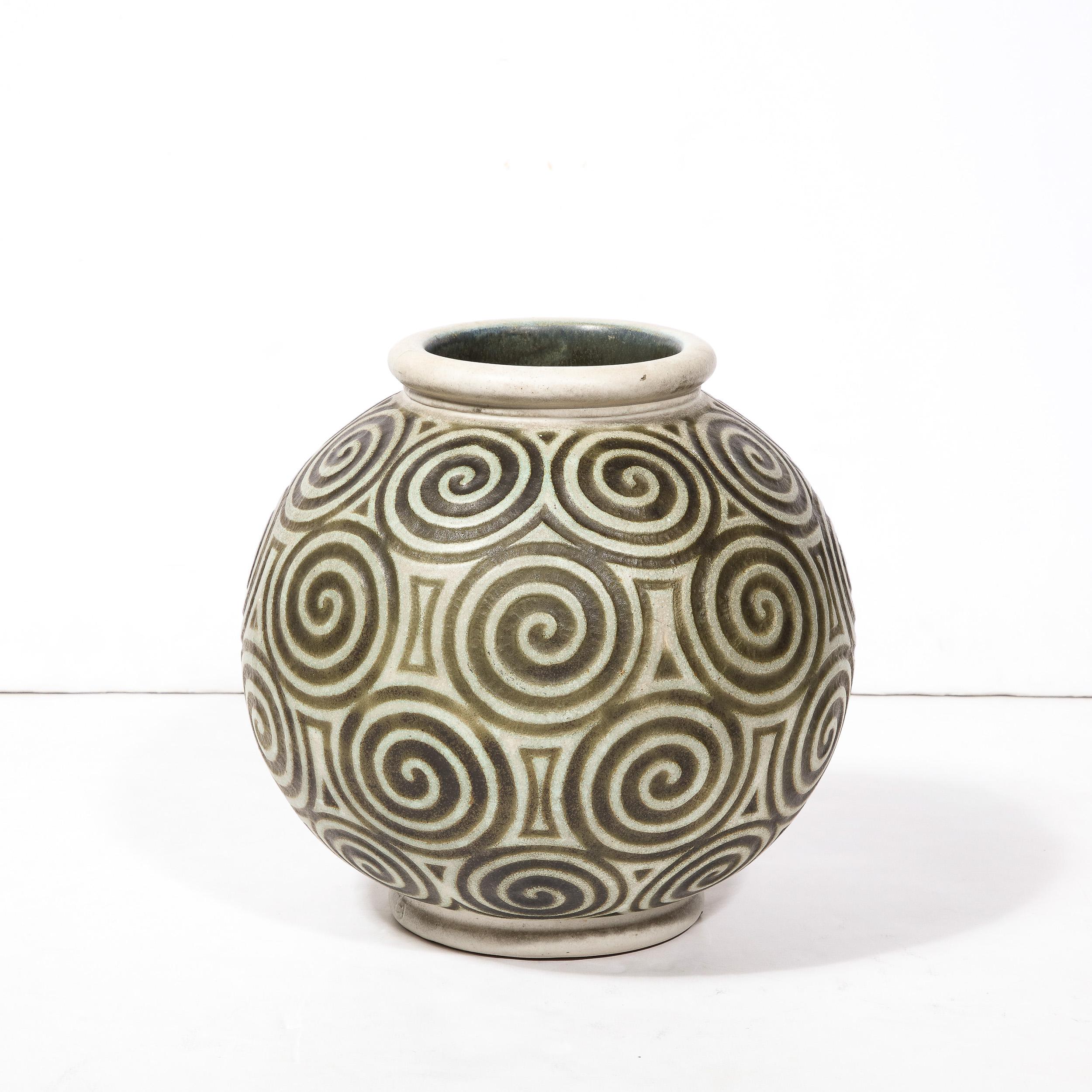 This striking ceramic vase originates from nancy, France Circa 1925. Spherical in form with two coiled bands composing the mouth and base of the vase, this Art Deco piece utilizes a repeating motif of relief carved spirals in contrasting hues of