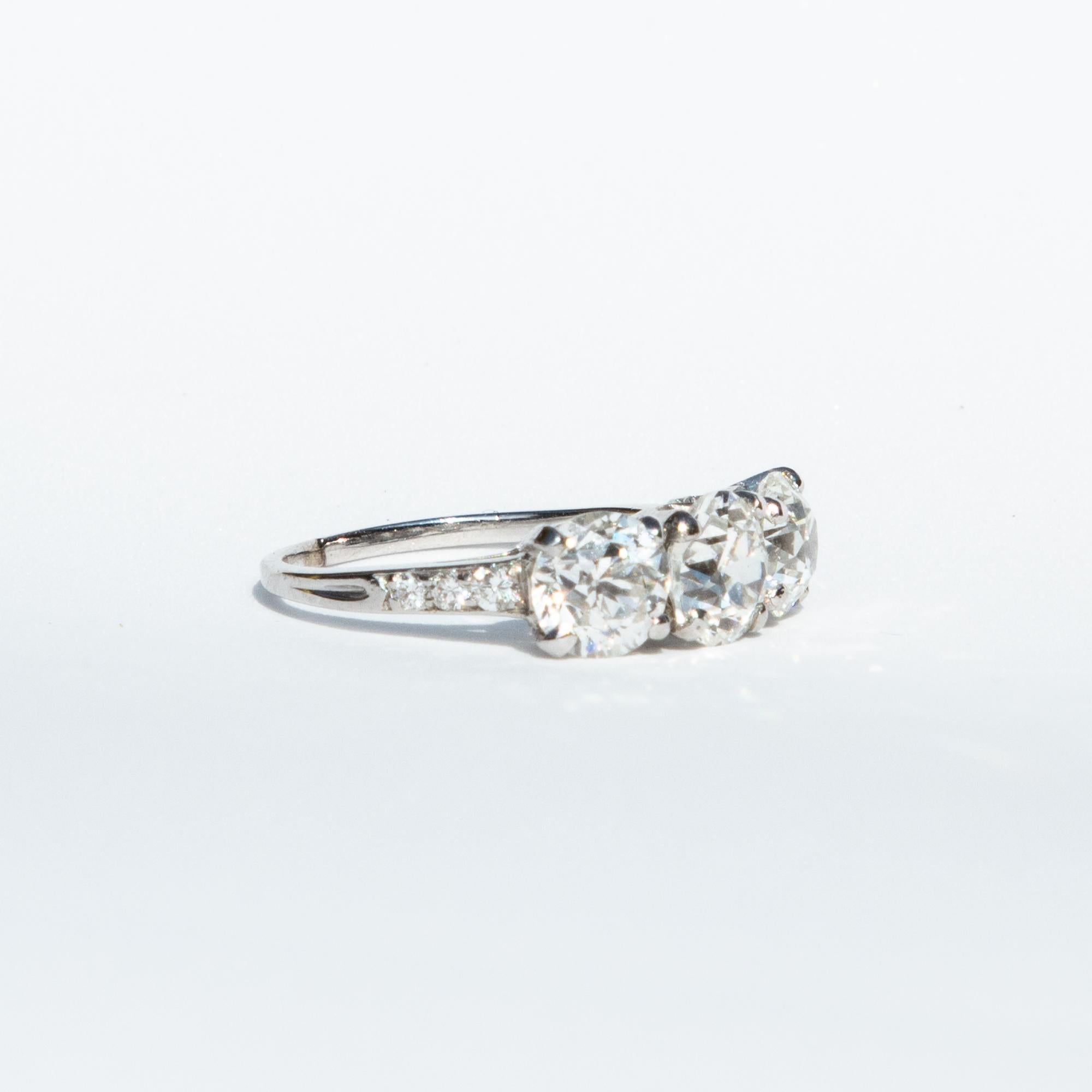 A incredible three-stone diamond ring crafted by the iconic Tiffany & Co. in 1925, during the height of the Art Deco era. The three principal cushion cut diamonds have a certified total weight of 3.15 carats, G/H colour ad VS1/SI1 clarity. Set in