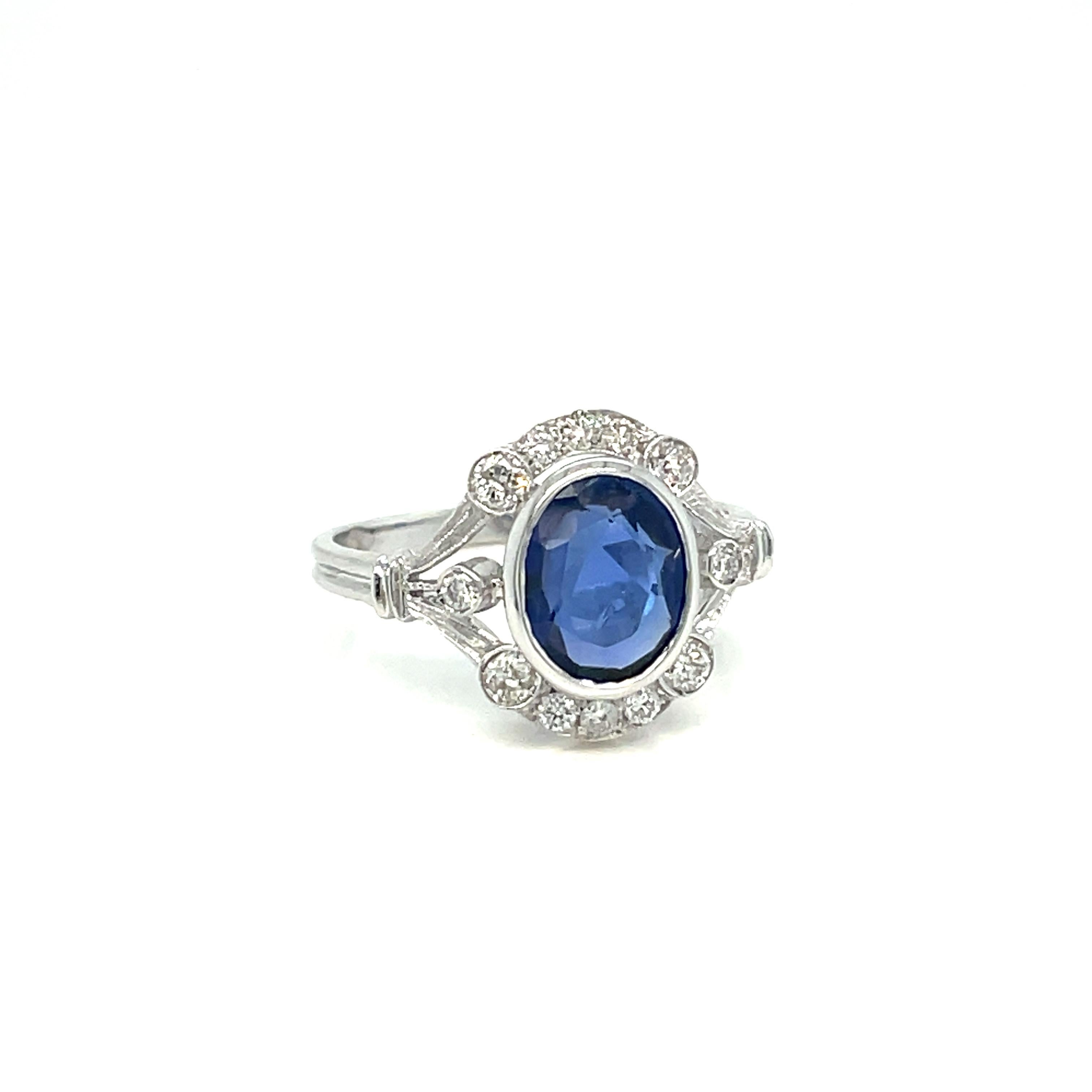 This beautiful Sapphire and Diamond Art Deco ring is hand crafted in solid 18k white gold and engraved in typical Art Deco design with Millegrain decorated aplique. 
It is set with a pleasant Blue oval cut Natural Unheated Burma Sapphire weighing