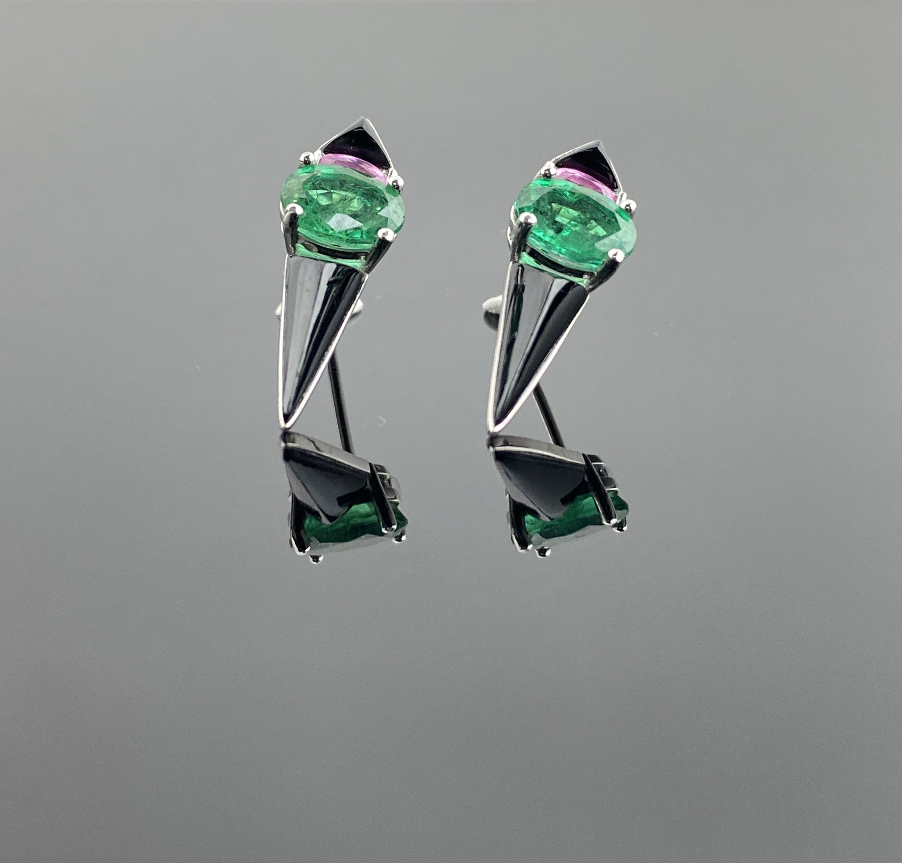 A pair of art-deco inspired earrings, with oval shaped 2.52 carat Zambian Emerald and oval shaped 0.60 carat Pink Sapphire, with 2.19 carat Black Onyx, all set in 18K White Gold. The earrings come with a push-pull backing. The earrings are around 1