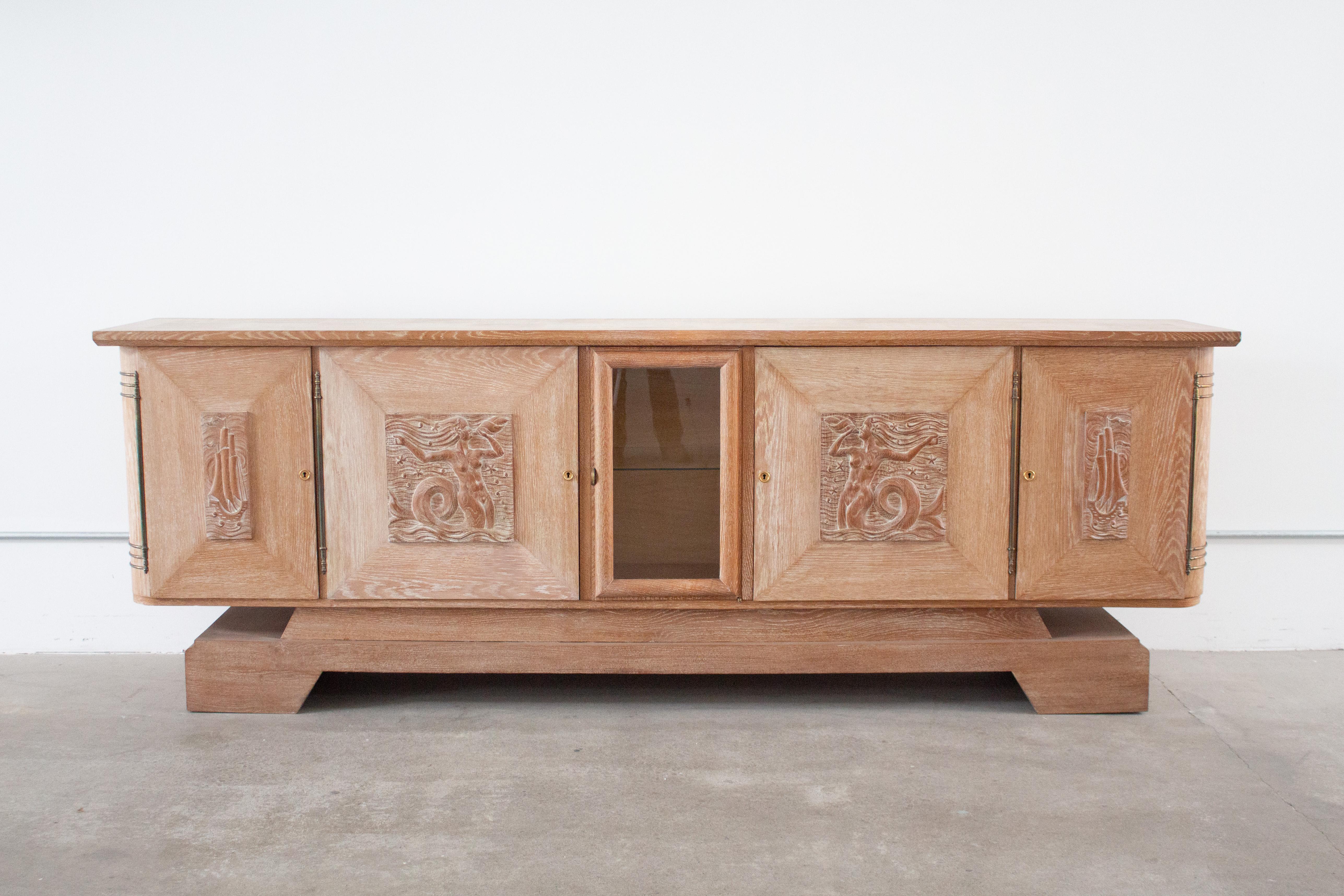 Monumentales Kredenzbuffet von Jean-Charles Moreux, Frankreich, ca. 1940er Jahre. Großer Maßstab mit klassischen Art-Deco-Merkmalen. Eichenholz in Keramikoptik mit Messingakzenten und Glasschrank in der Mitte. Skurrile Reliefschnitzereien von