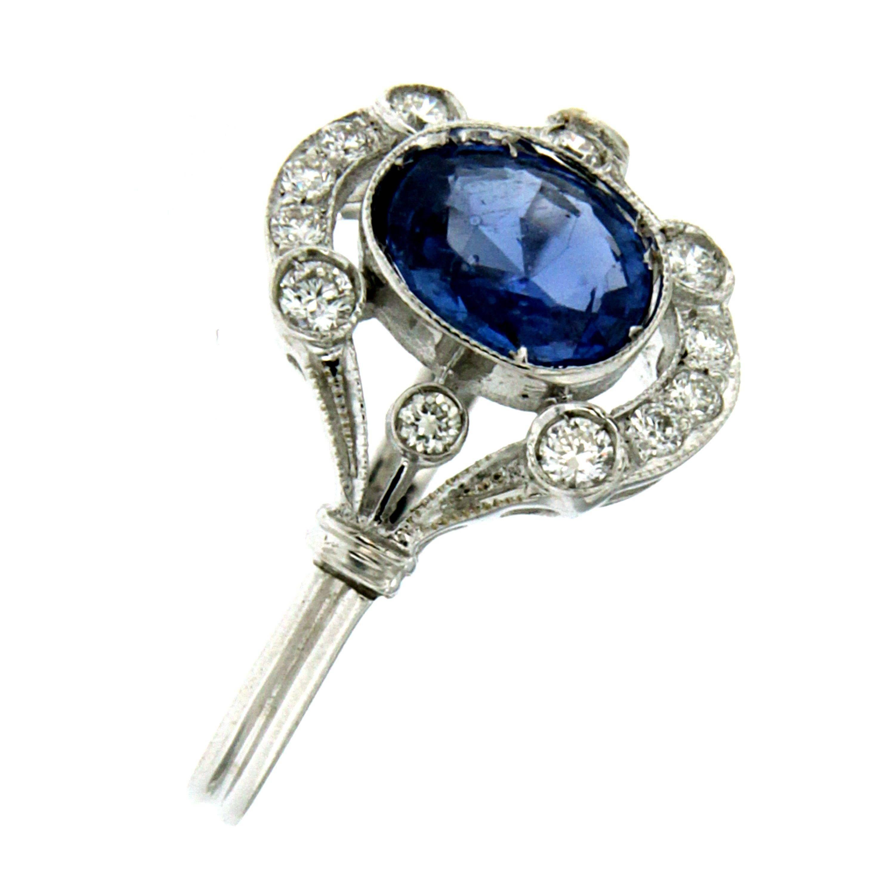 This beautiful Sapphire and Diamond Art Deco ring is hand crafted in solid 18k white gold and engraved in typical Art Deco design with Millegrain decorated aplique. 
It is set with a pleasant Blue oval cut Natural Ceylon Sapphire weighing 1.40