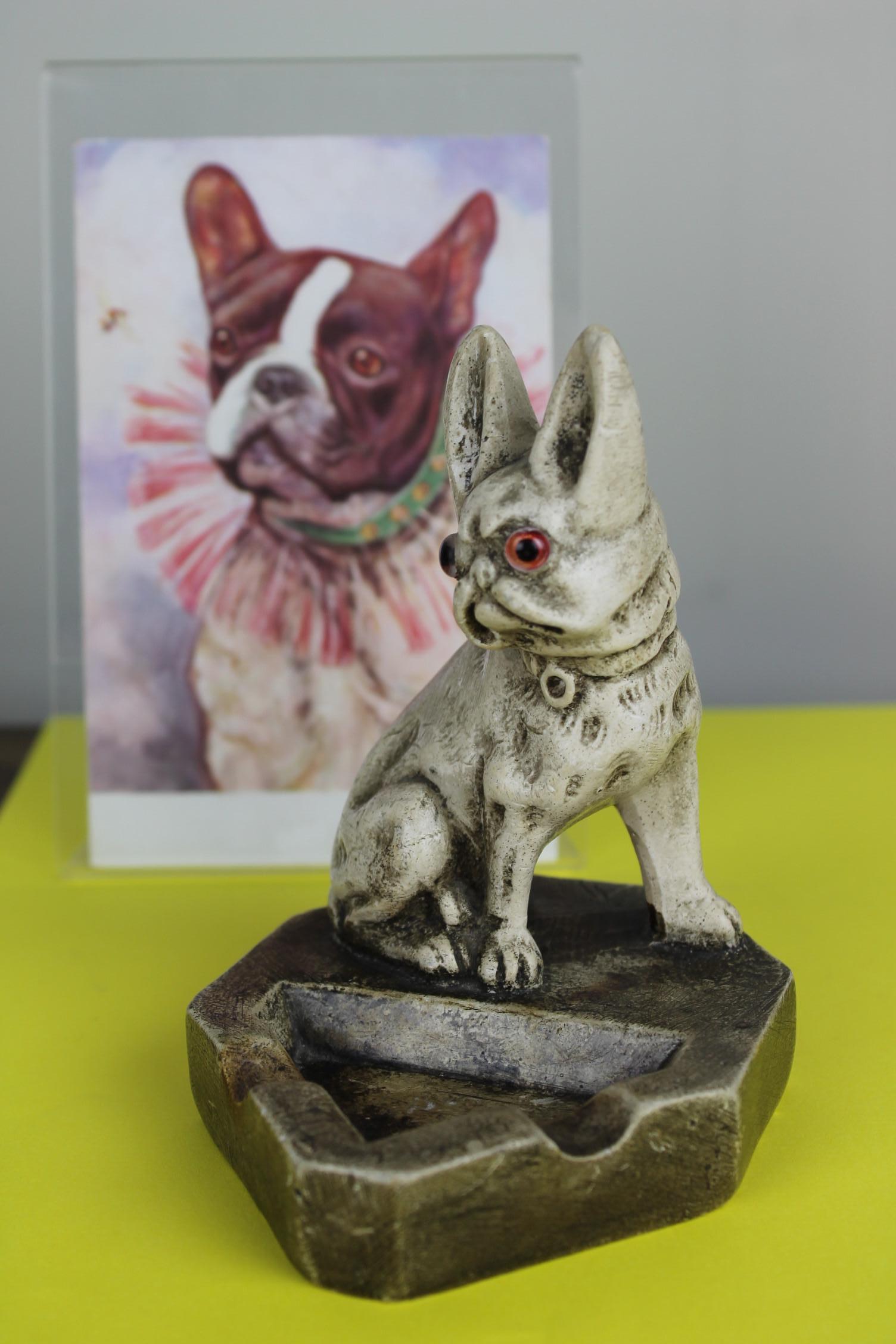 Art Deco Chalkware Ashtray with a French Bulldog Sculpture on. 
The Bulldog Statue has glass eyes and big ears.
This painted plaster ashtray from the Early 20th Century can be used as a desk accessory or be placed as a bulldog collectable sculpture.
