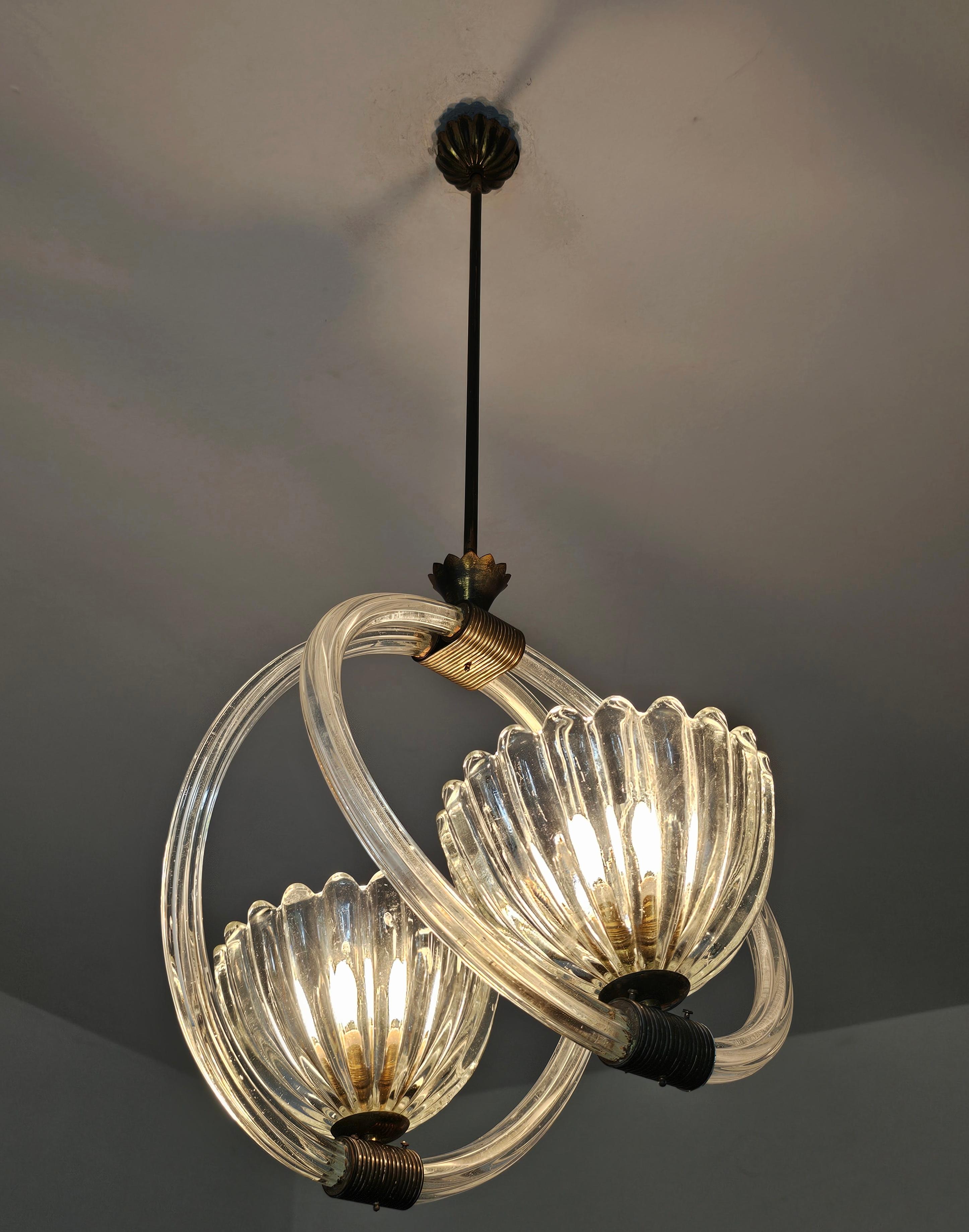 In questo annuncio troverai uno splendido lampadario doppio in stile Art Déco attribuito a Barovier&Toso. È realizzato nello stile caratteristico dell'azienda, con due anelli di vetro fissati con ferramenta in bronzo e con due bellissimi paralumi a