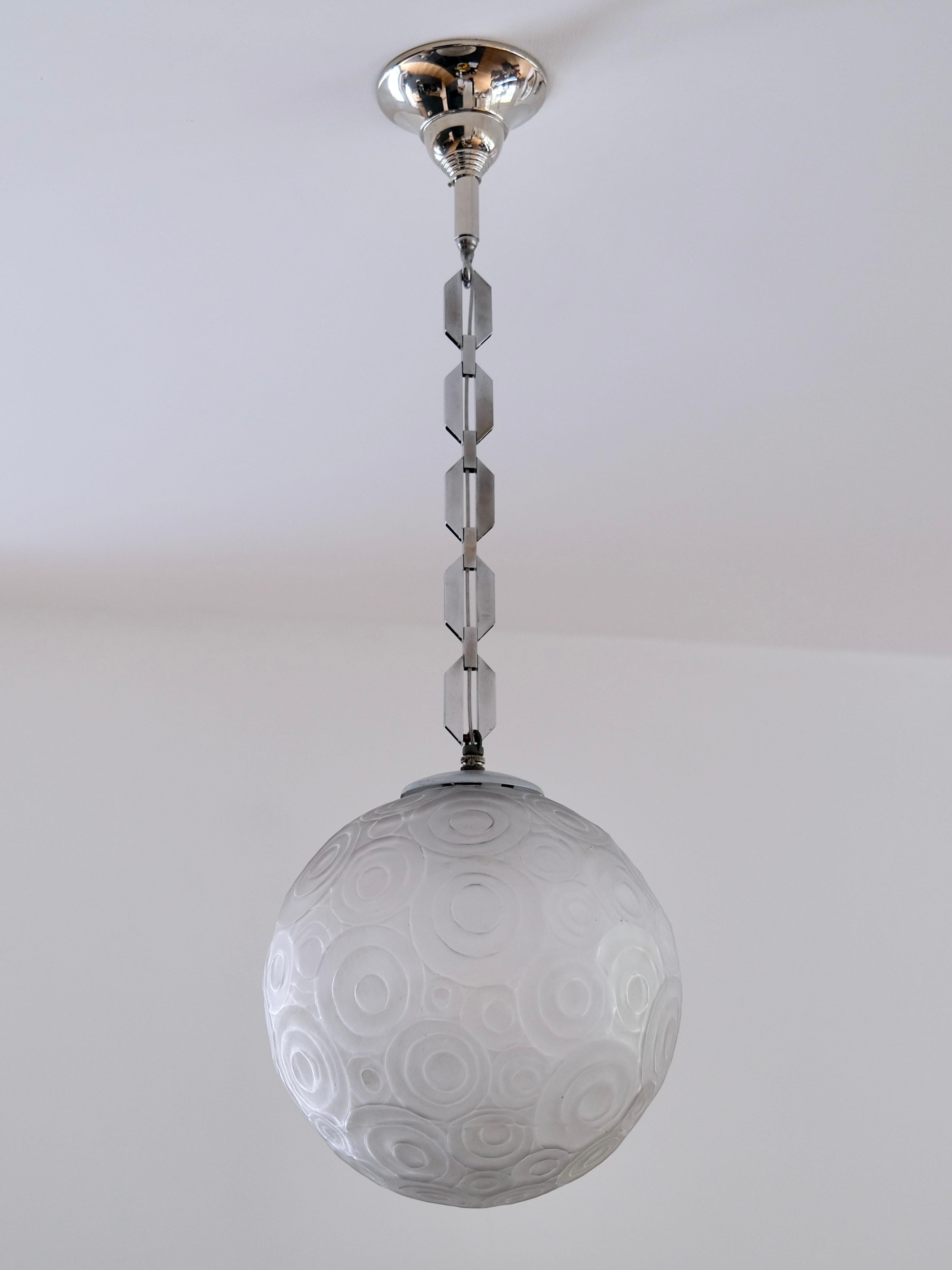 Step into the opulence of the 1930s with this extraordinary Art Deco chandelier by renowned French designer Marius Ernest Sabino. Crafted with impeccable precision, this statement piece features a stunning glass ball adorned with intricate geometric