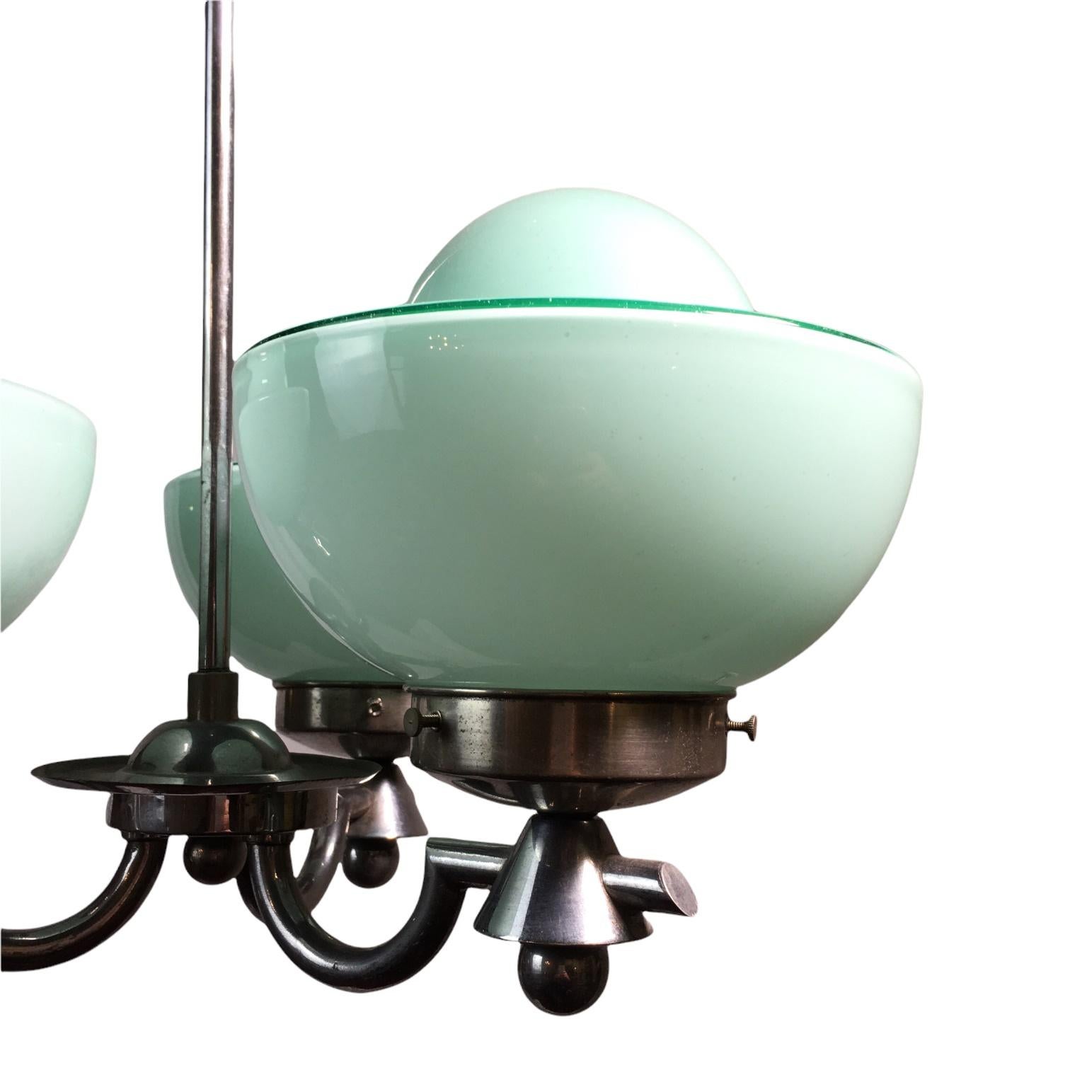 An unusual Art Deco three-arm chandelier in chromed metal with three curved arms with lovely pale blue-green cup-shaped opaline shades. 

- Manufactured in Germany approximately 1930
- Measures: Lampshade height 8 cm, diameter of the globe