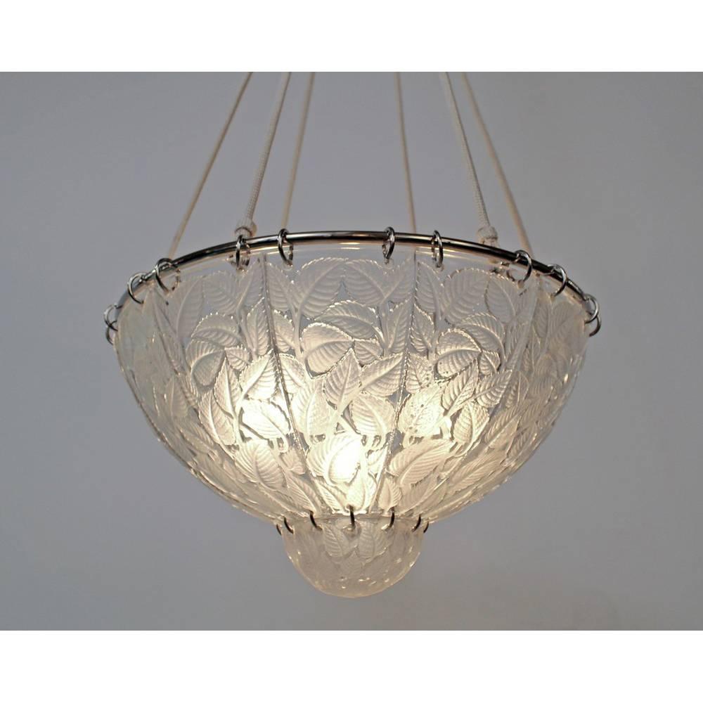 A clear and frosted molded glass chandelier by R. Lalique in the Feuilles de Charme design, depicting foliage
Made in France 
Model created in 1921
Signature: R. Lalique
Reference: Lalique by Marcilhac, page 642.