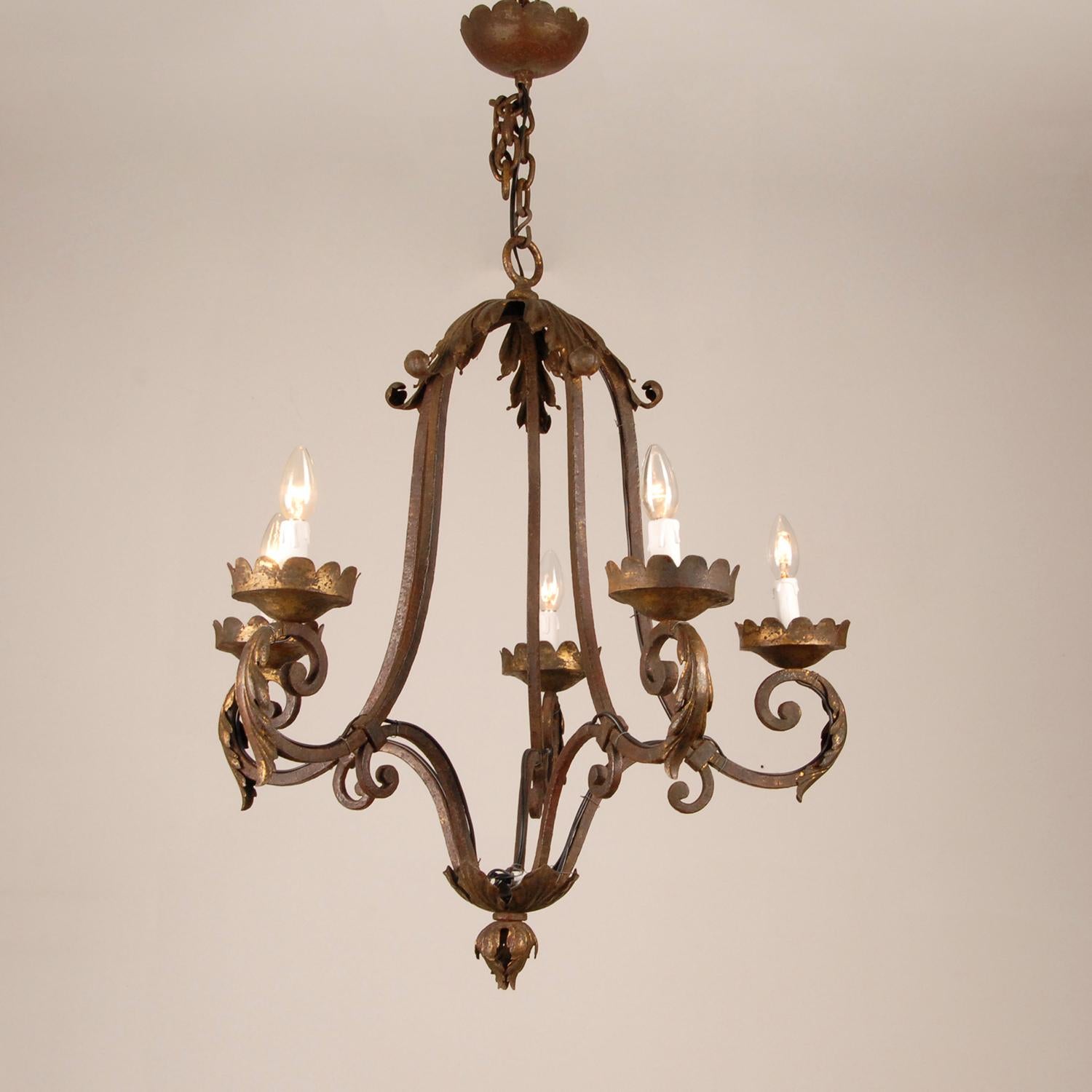 Wrought iron Art Deco cage 5 light chandelier - lantern.
Hand crafted wrought iron cage frame with 5 arms for E14 light bulbs.
On top a crown of acanthus leafs with traces of gold leaf.
The cage body has gained a very stunning time patine in the