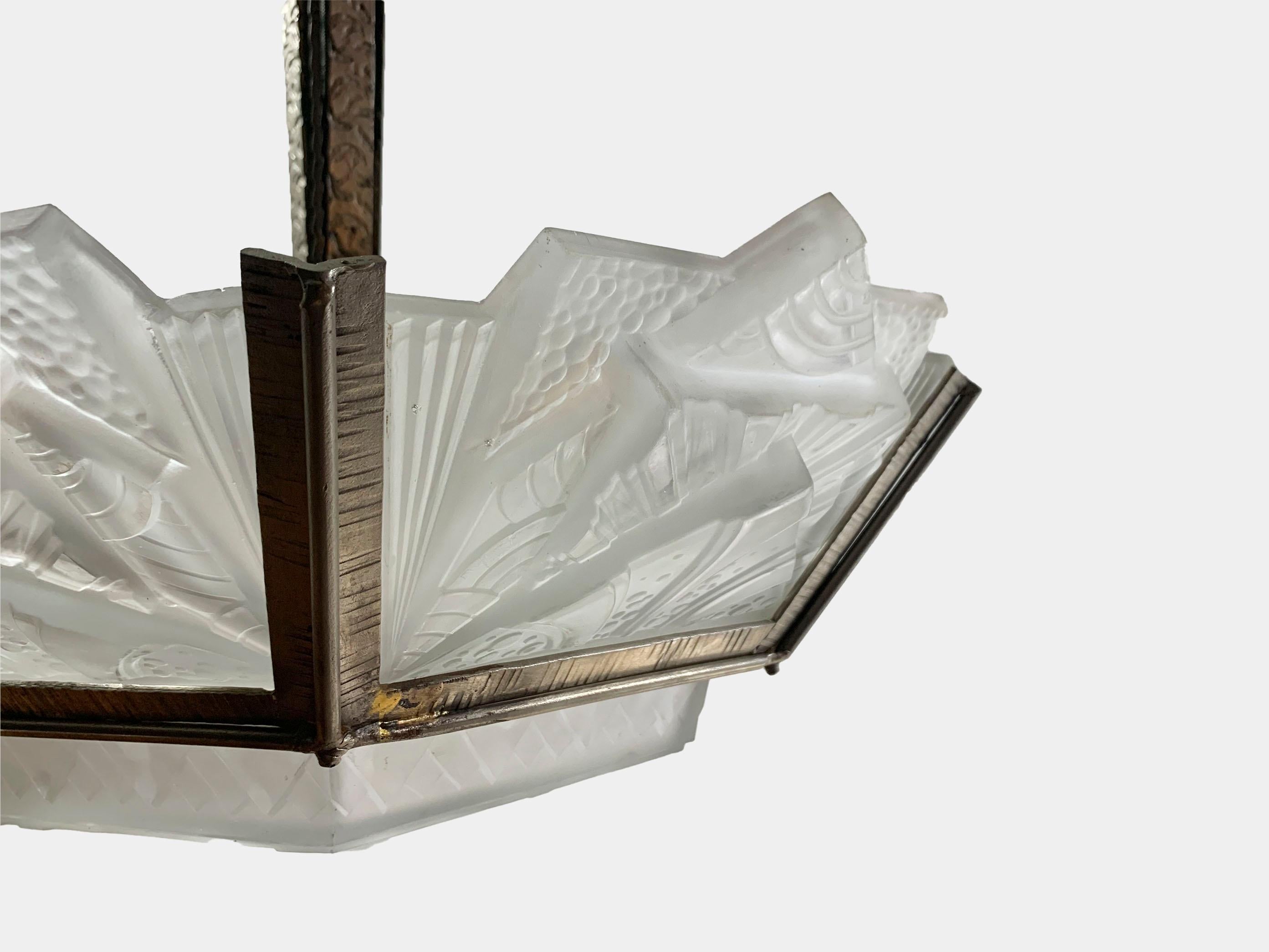 Lustre géométrique Art Déco français, il se compose d'une structure en bronze supportant les 6 abat-jour en verre moulé pressé et la vasque de la pièce centrale, le tout portant la signature de Muller Frères Luneville. Fabriqué en verre dépoli