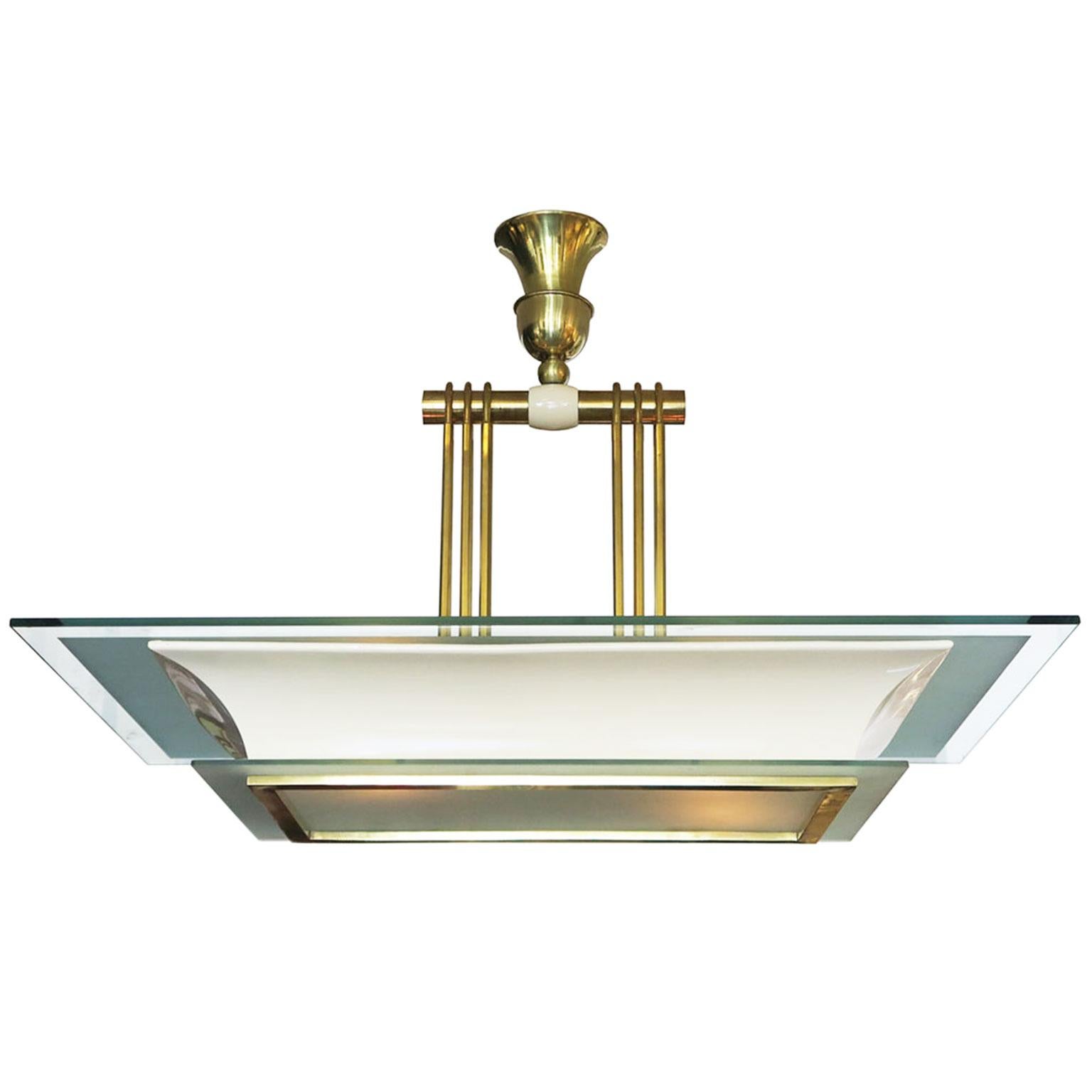 This classic Art Deco chandelier features a lacquer on metal frame with aged brass details on the stem, canopy and lower glass. There is a rectangular overhang on the top as well as a frosted glass bottom section emitting the light.
 