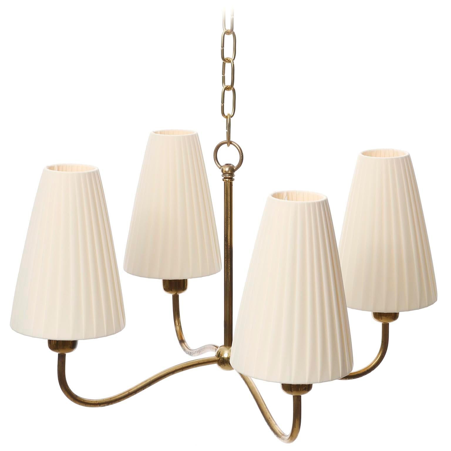 A fantastic pendant light attributed to Josef Frank, manufactured in Austria in 1930s.
The fixture is made of brass with ball in the center that holds four organically curved arms with cream-colored pleated fabric shades.
The brass parts have patina