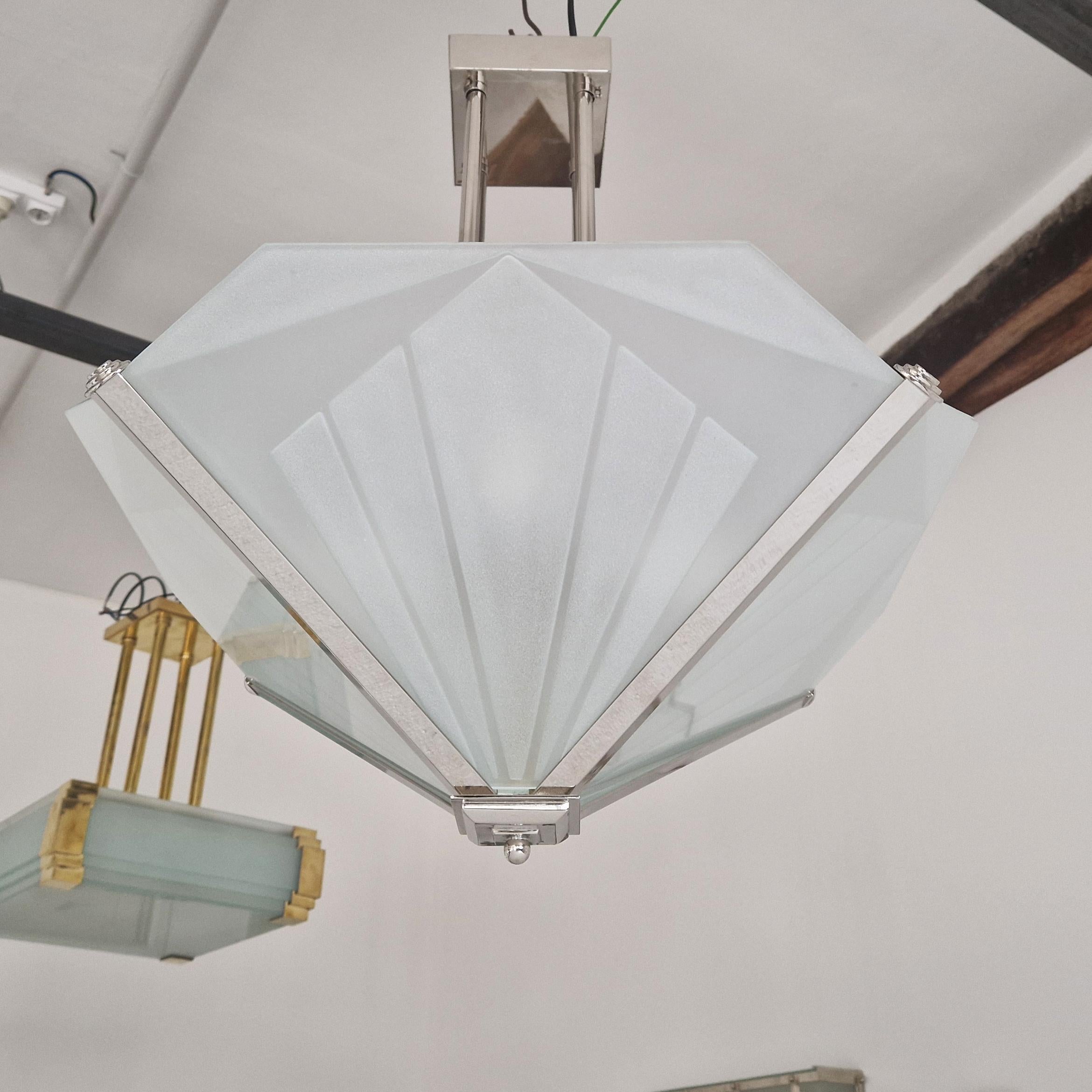 The Art Deco chandelier in nickel-plated bronze and sand-cut glass is a luminaire that reflects the aesthetics of the era, measuring 48x48 cm with a height of 55 cm. Manufactured using traditional techniques, it features meticulous work of bronze