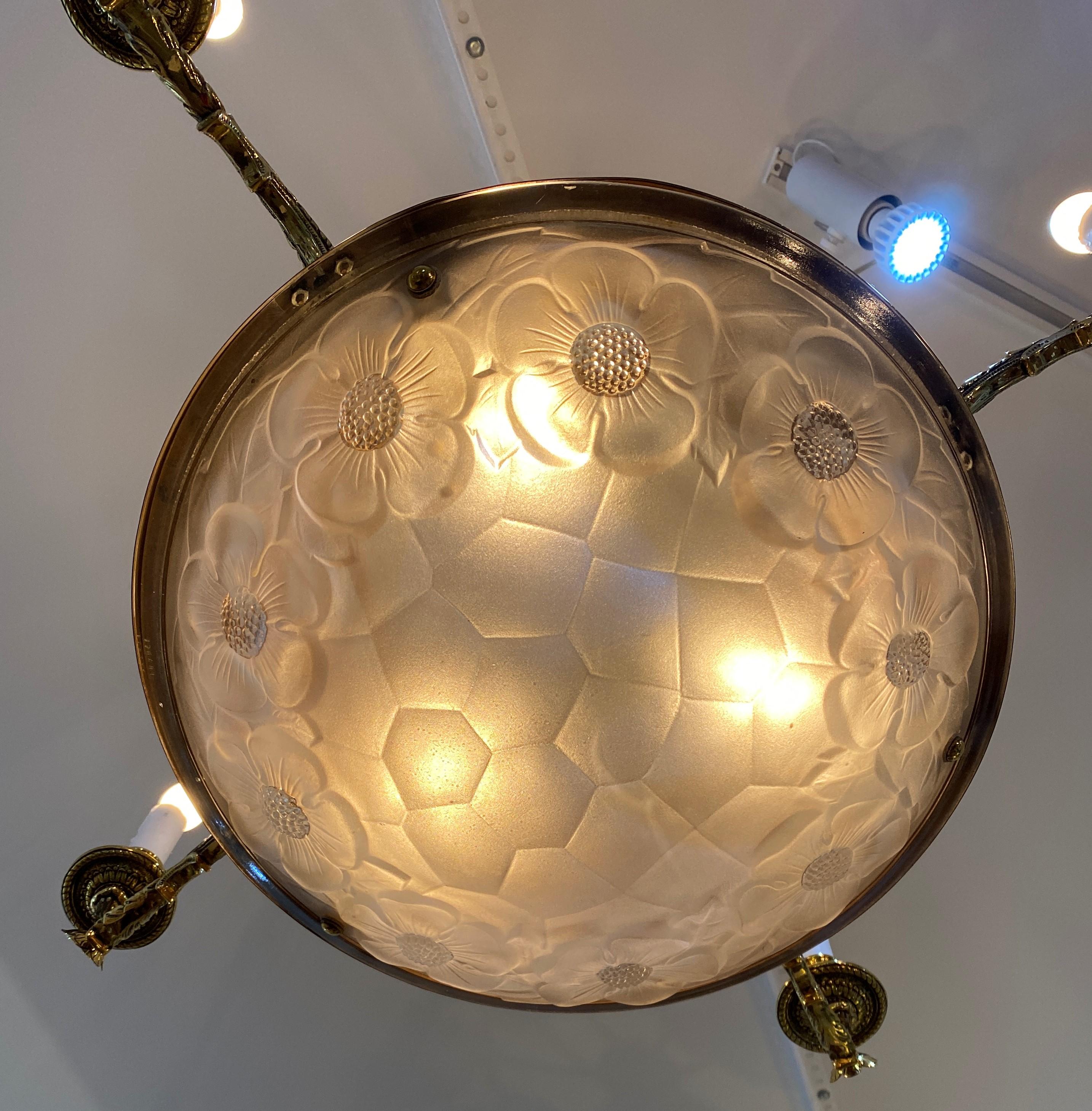 This stylish chandelier seem to be a transitional piece with classical brass hardware and Art Deco satin glass globe. 

Note: The satin glass Lalique style globe with its stylized dogwood blooms and leaves is signed.

Note: Requires four candleabra