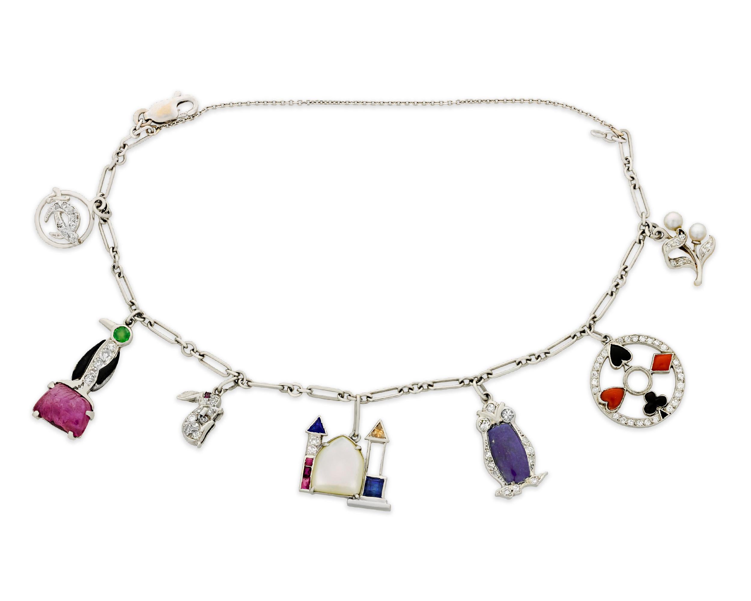 This delightful platinum Art Deco-period charm bracelet exudes a playful whimsy. The charms include a variety of jovial motifs, including a bunny, a penguin, an owl, a castle, a pearl flower, playing card suites and a sword symbol. Each charm holds