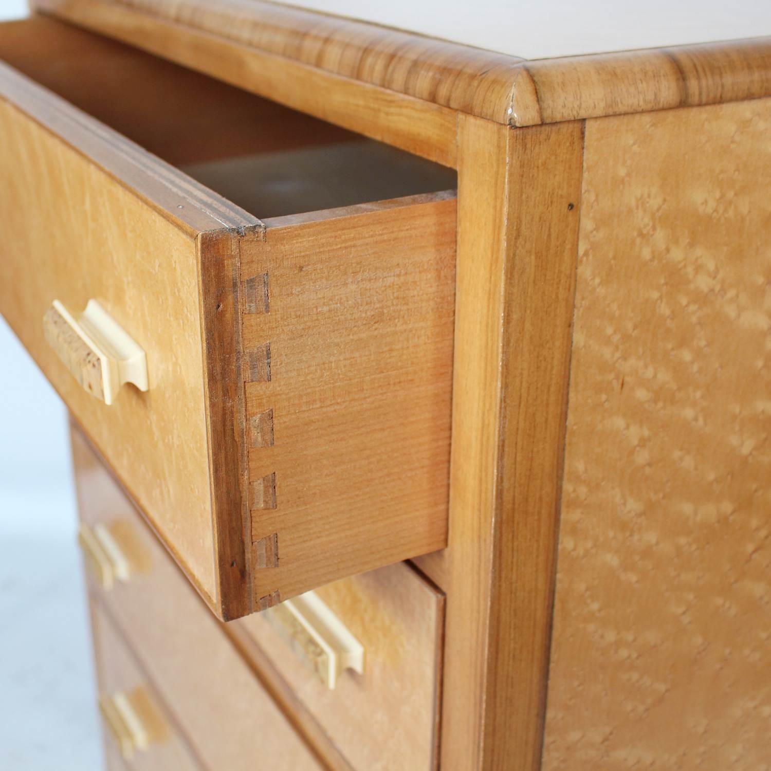 An Art Deco chest of drawers in figured bird's-eye maple with walnut banding and original bi-colored bakelite handles.