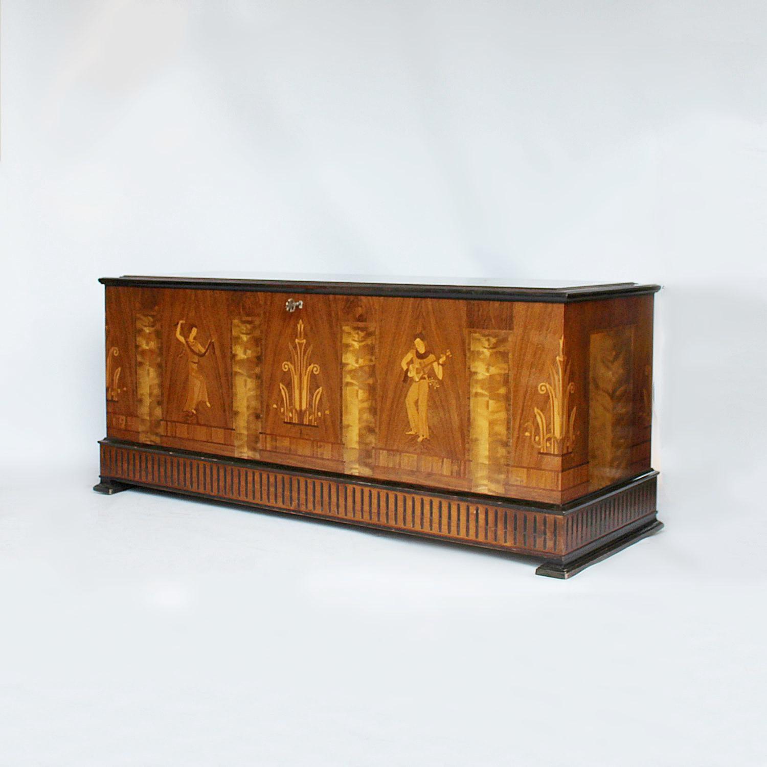 An Art Deco chest with inlaid design to front and corners in a variety of woods - boxwood, Macassar ebony, straight grain walnut, satinwood. Carved base and feet. Mahogany interior with integral shelving. Dated 1937 to front.
 