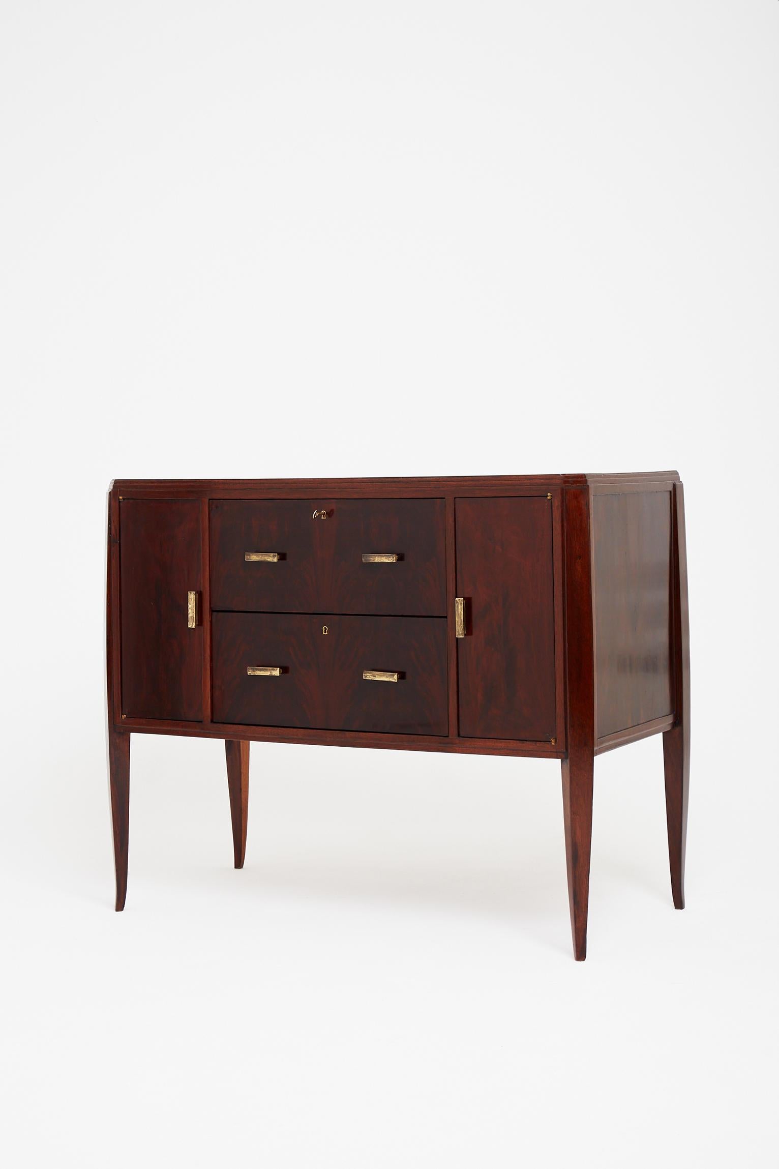 An Art Deco flamed mahogany chest of drawers, the two oak-lined drawers flanked by two cupboards, opening with brass handles, the stpped and canted corner top and body resting on elegant 'coup-de-fouet' legs.
Bearing the maker's label: G.E.J